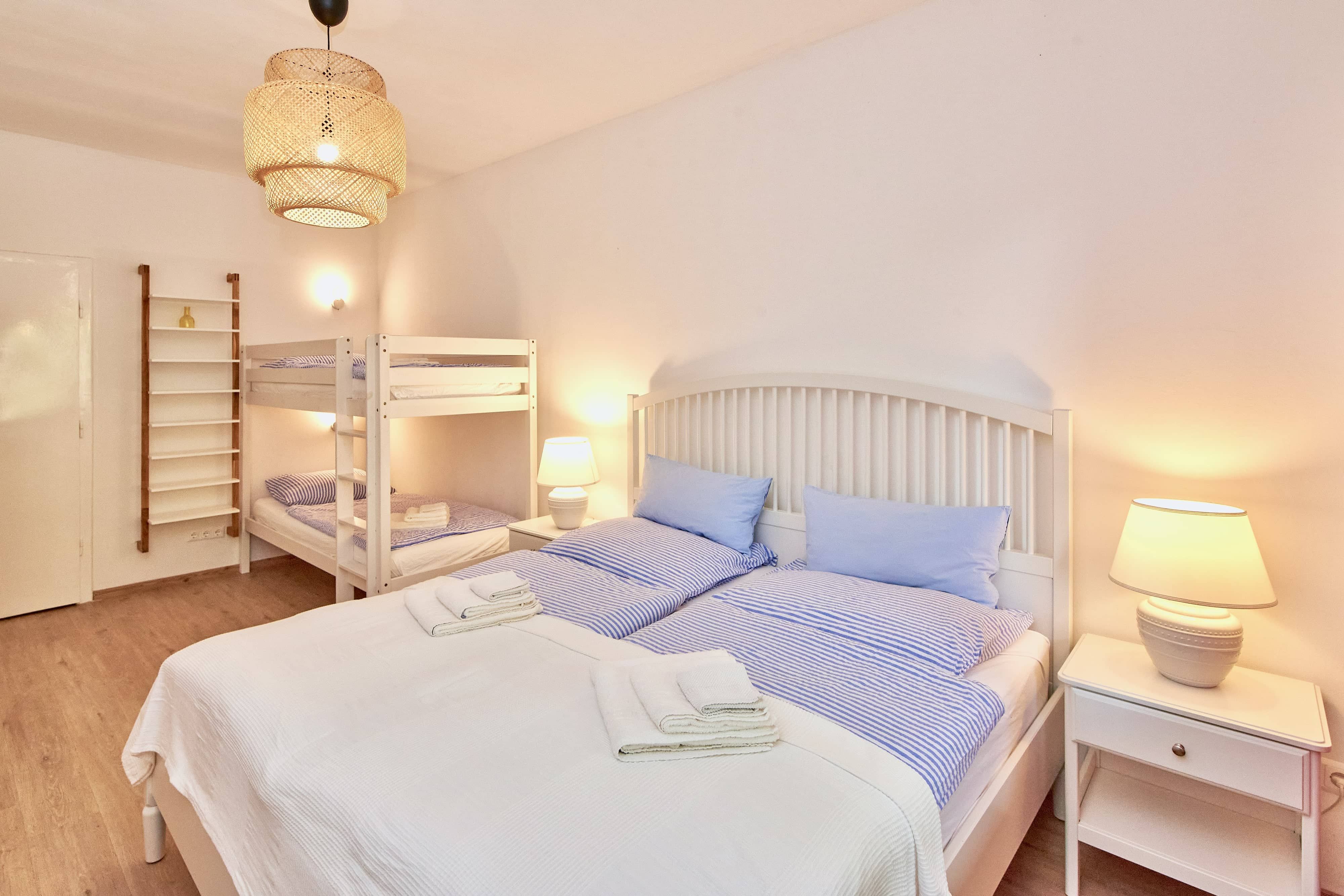 Bedroom with double bed, bunk bed, bedside lamps and bright furnishings.