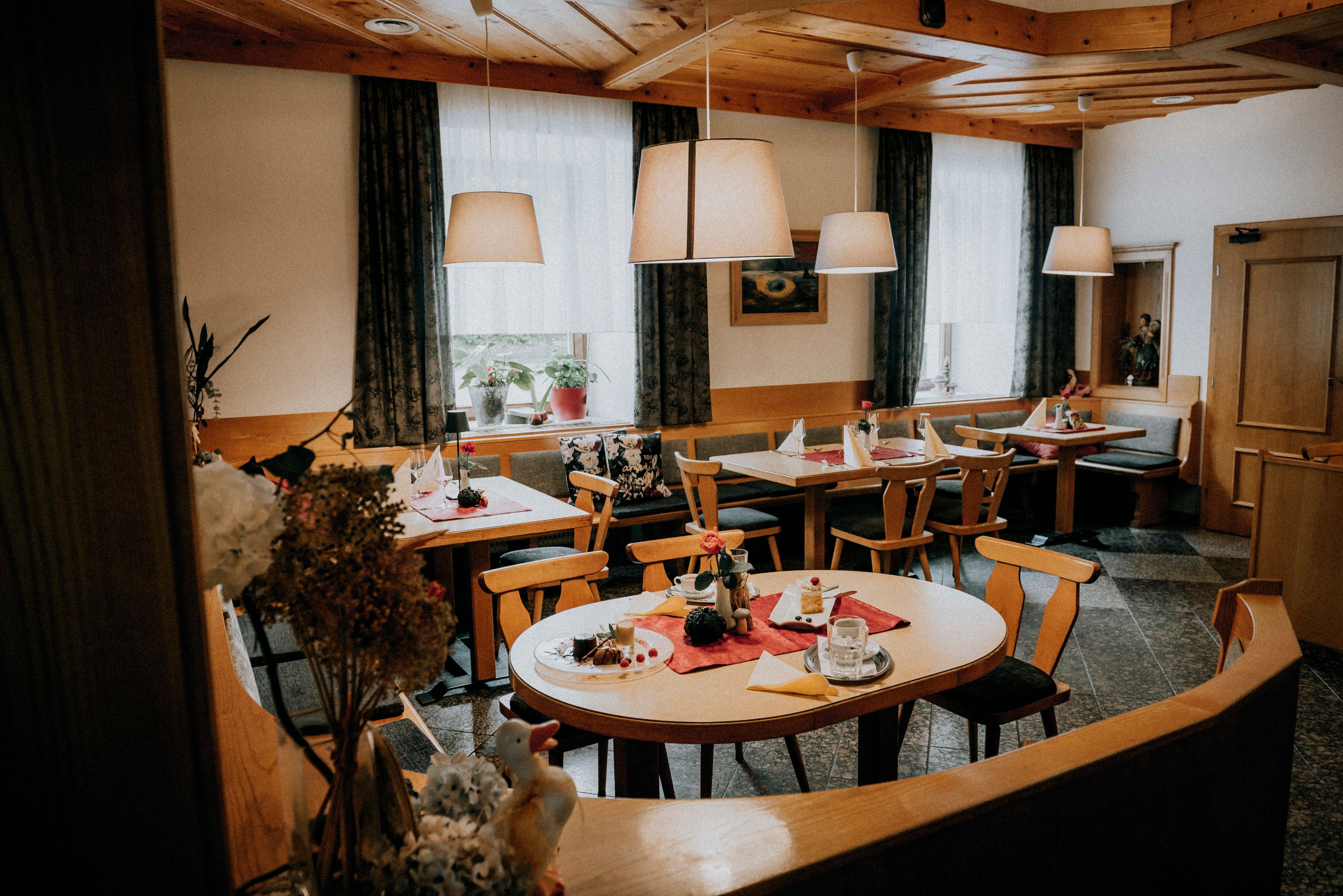 Cozy dining room with wooden furniture, set tables and hanging lamps.