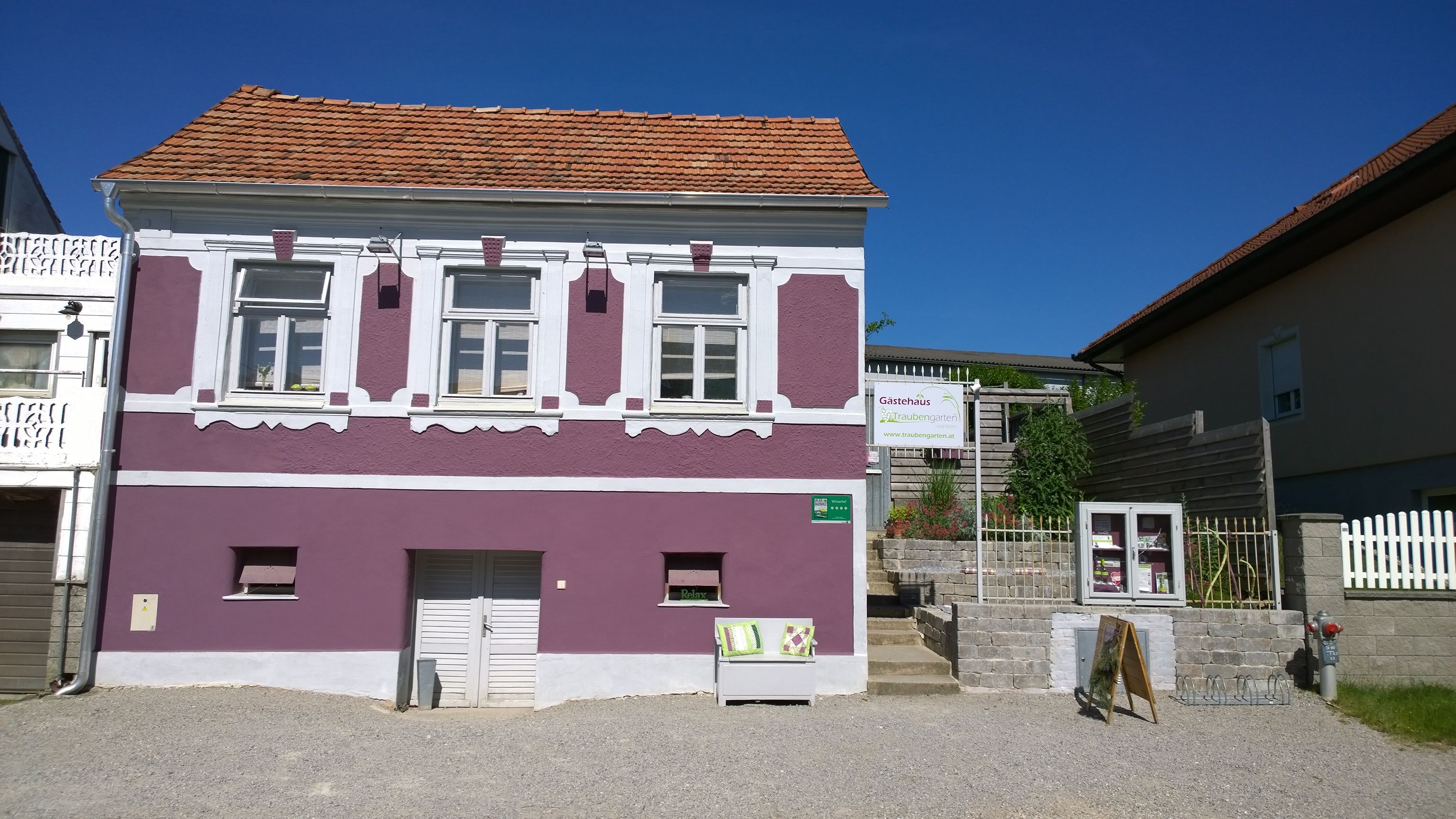 Exterior view of a purple house with white window frames and a sign for a guest house.