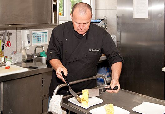 A chef cuts an omelette in a professional kitchen.