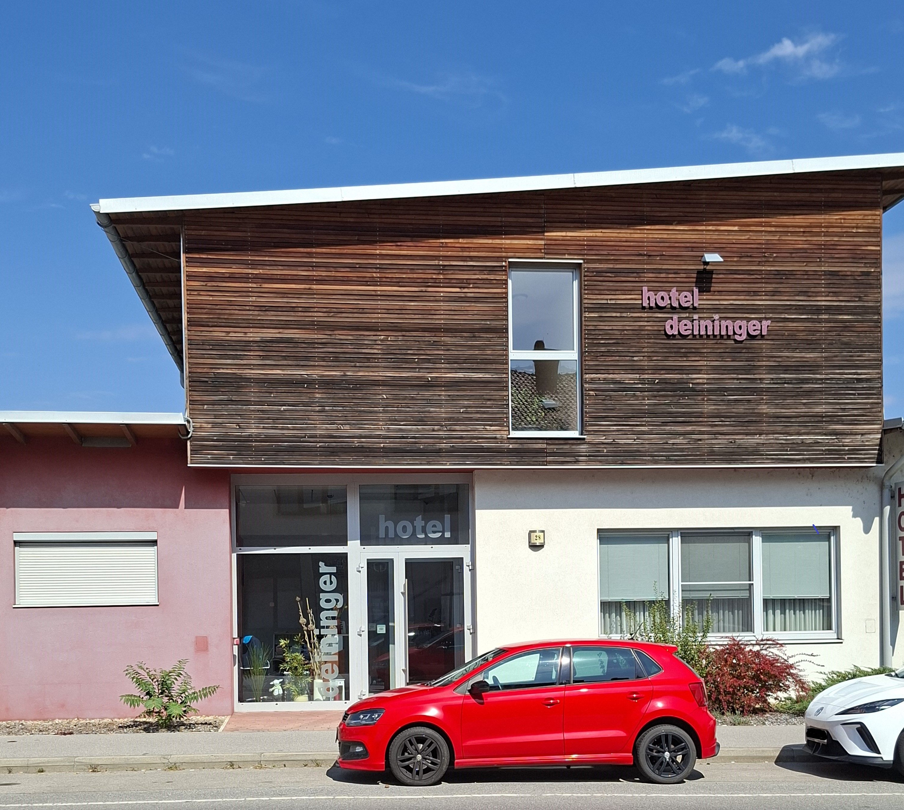 Facade of the Hotel Deininger with a red car in front of it.
