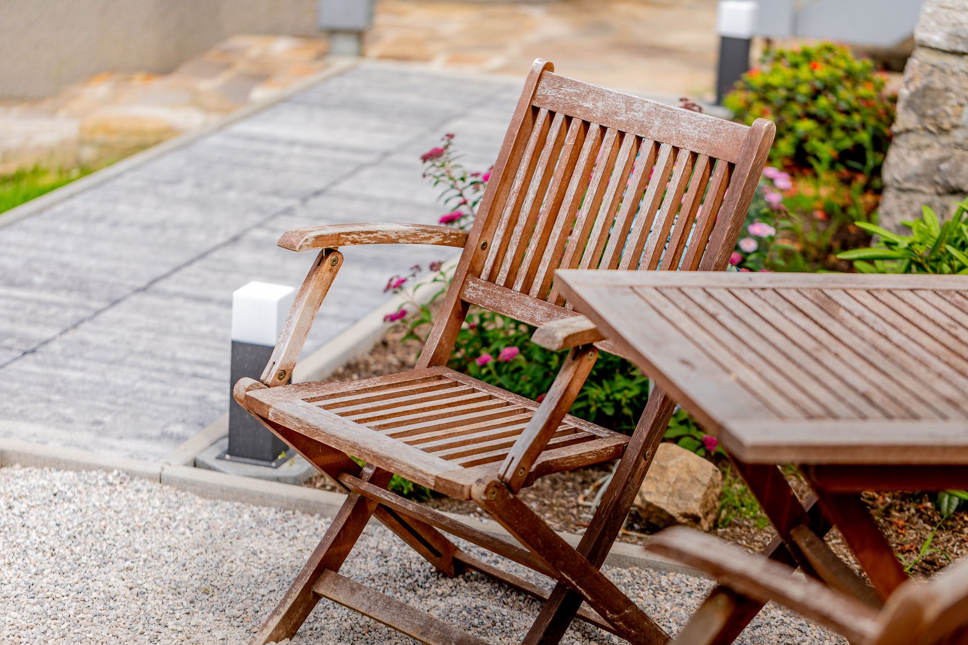 Wooden chair and table in the garden with flowers in the background.