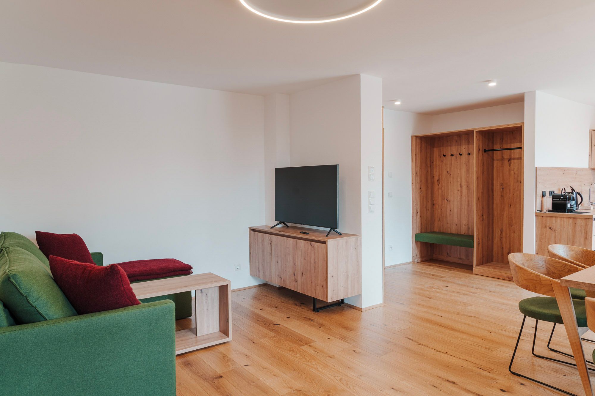 Modern living room with green couch, wooden furniture and a flat screen TV.