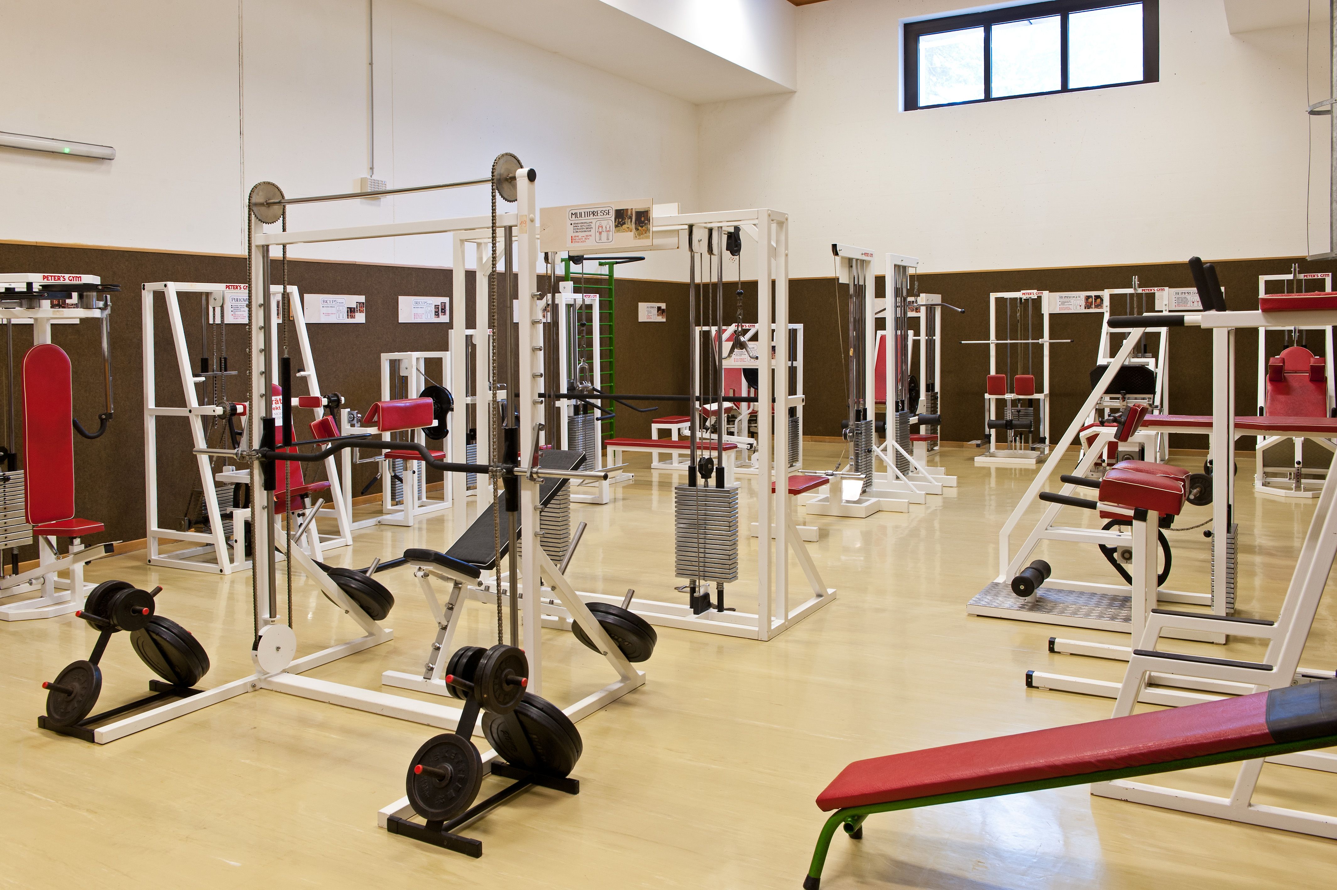 Fitness studio with various exercise machines and red cushions.