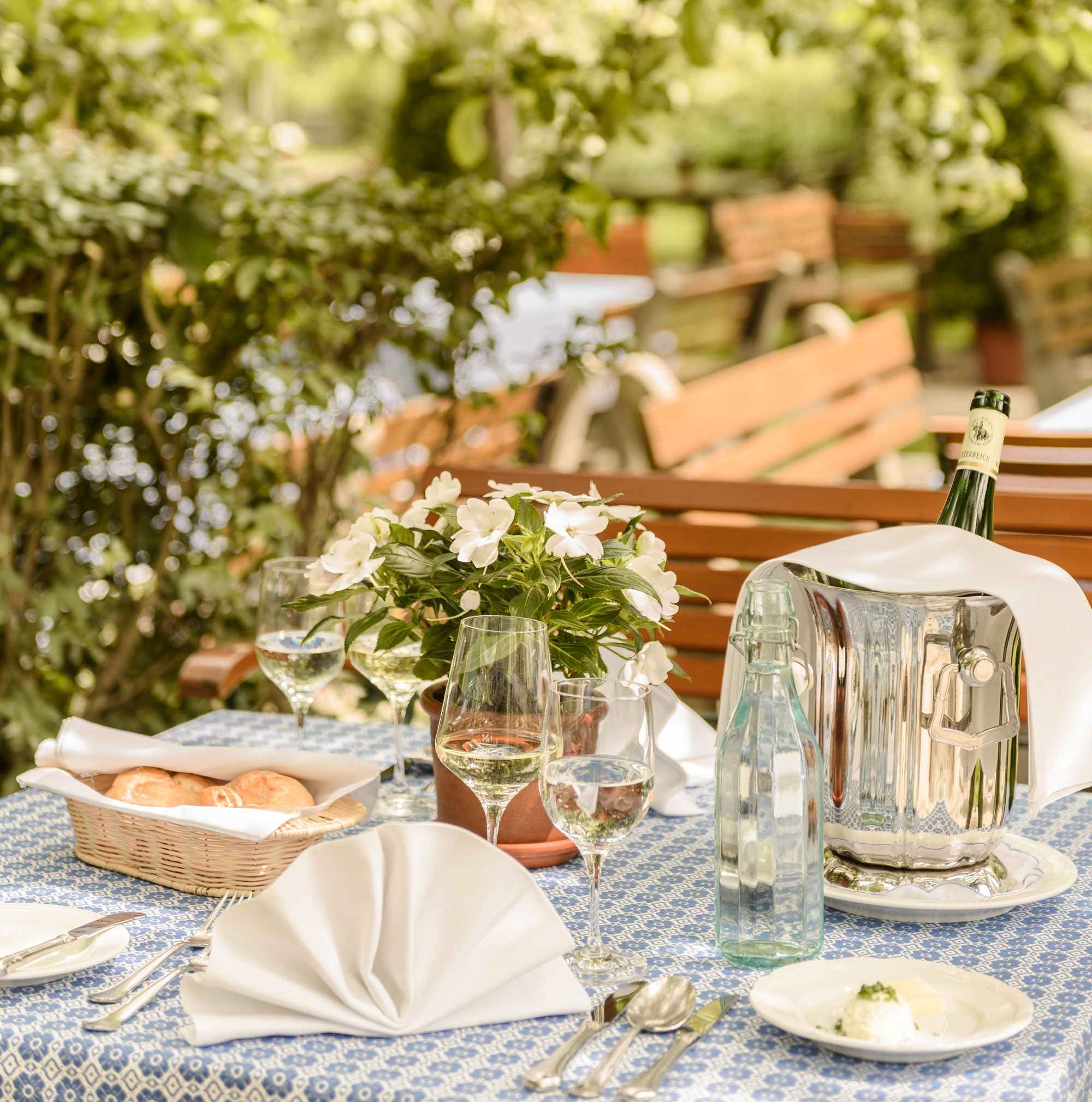 Table set in the garden with flowers, wine and water.