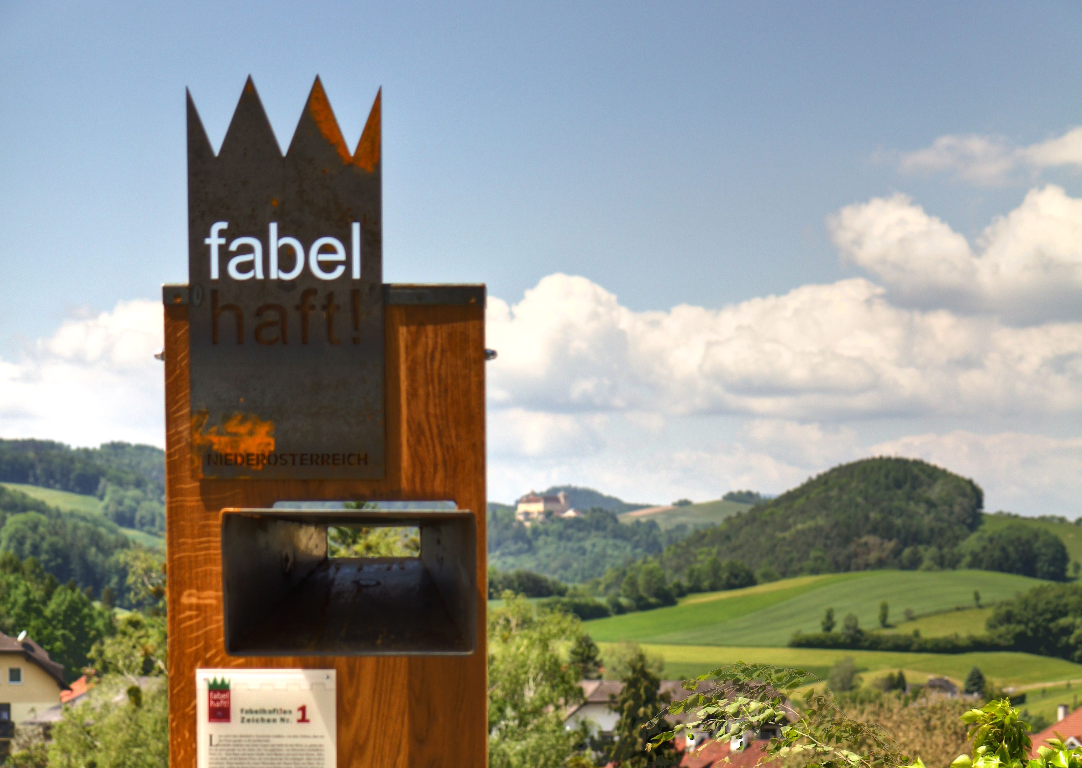 Metal sculpture with the inscription 'fabulous!' in front of a hilly landscape in Lower Austria.