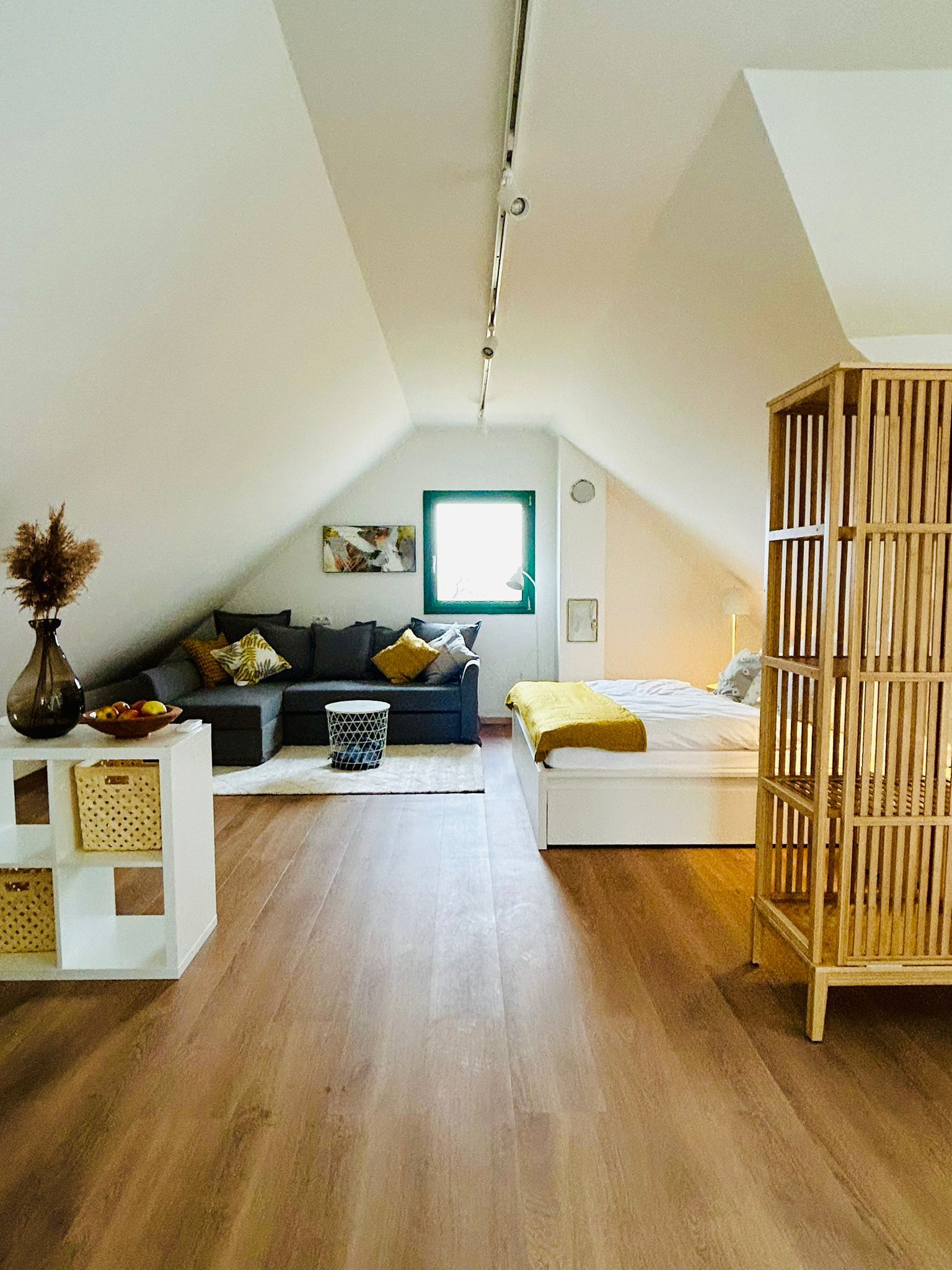 Cozy attic apartment with sofa, bed and wooden floor.