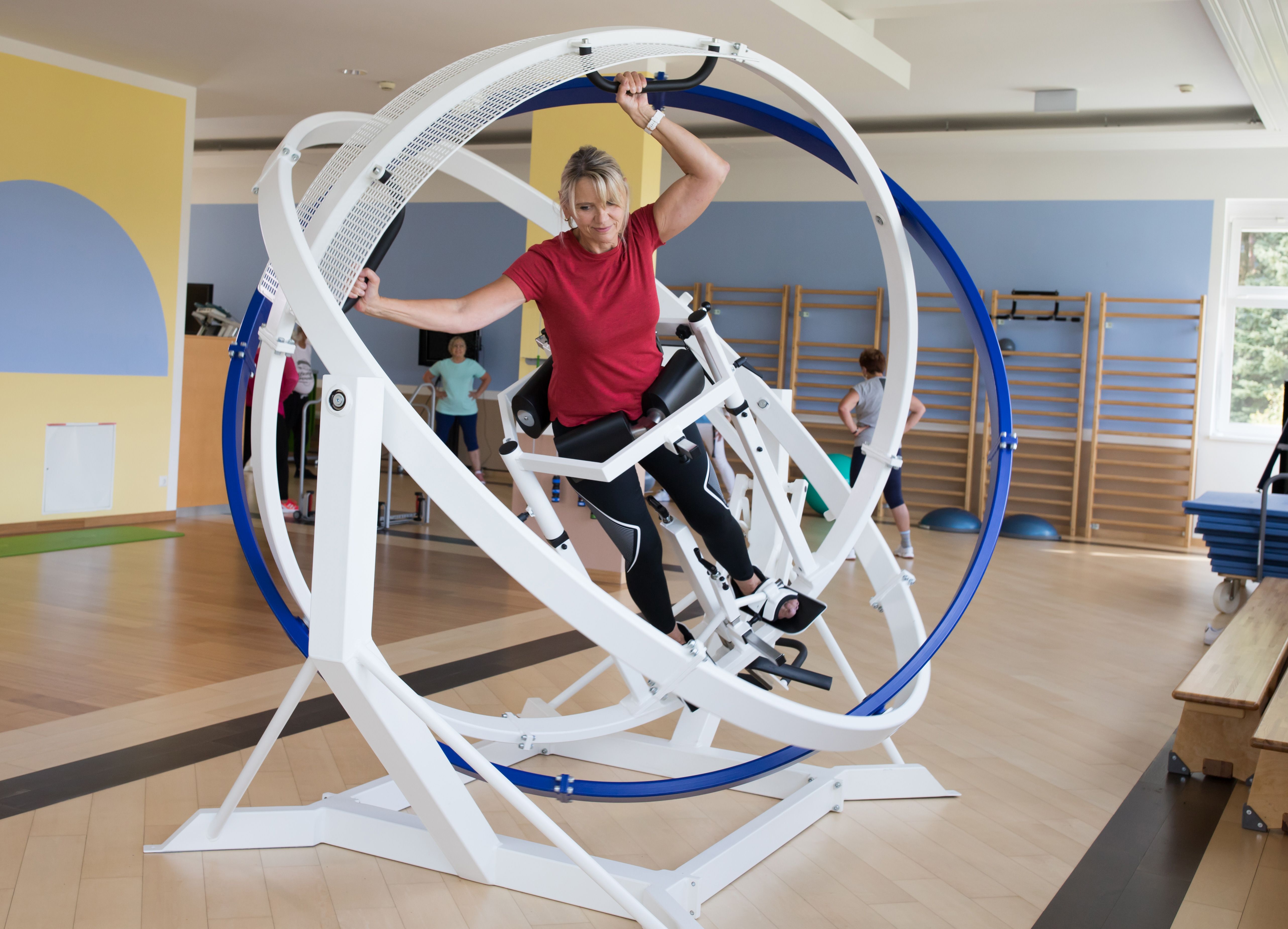 A woman exercises on a fitness machine with rotating rings in a fitness studio.