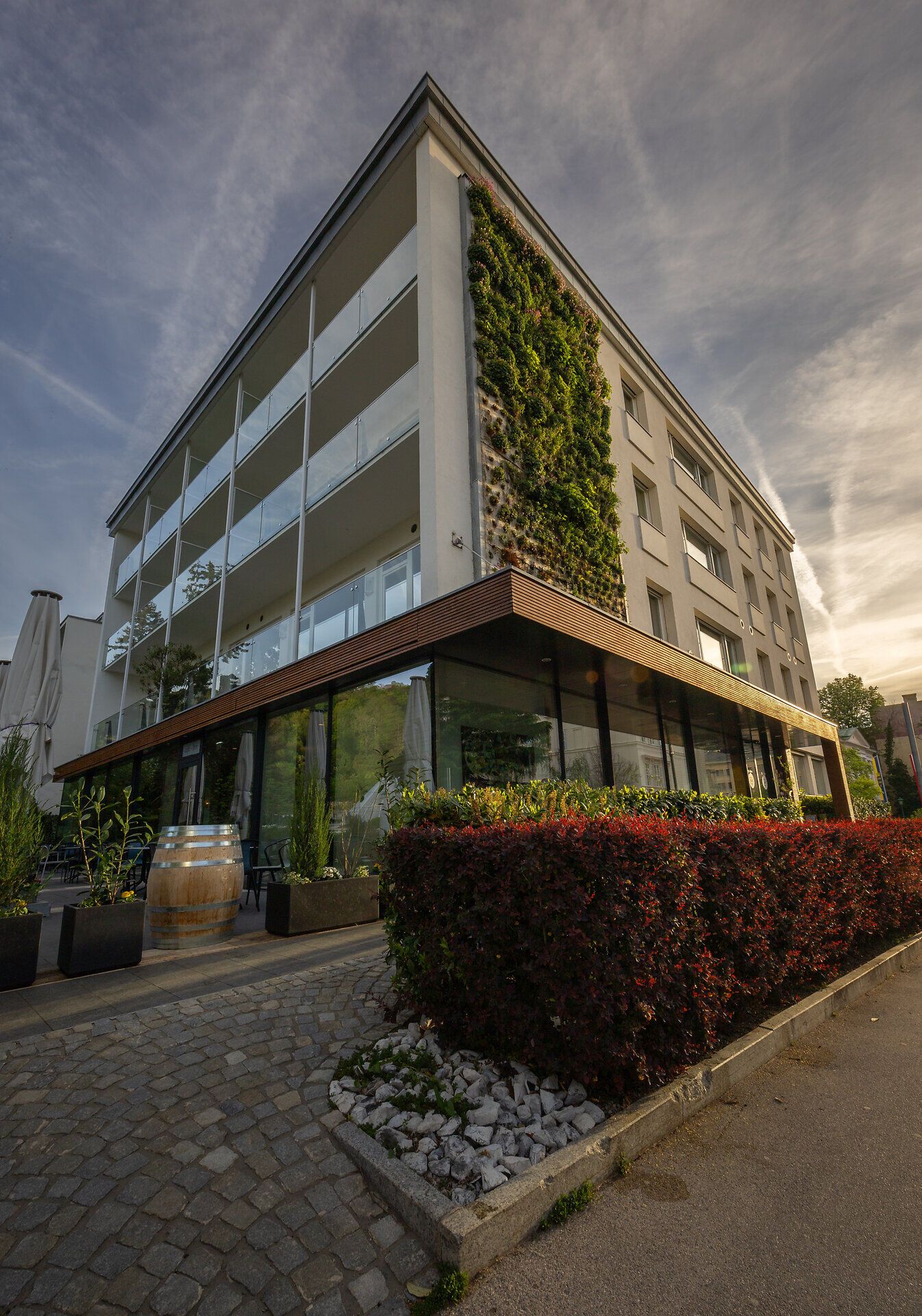 A stylishly furnished hotel room with a large red shoe as a bookshelf, antique chairs, a table and a floor lamp.