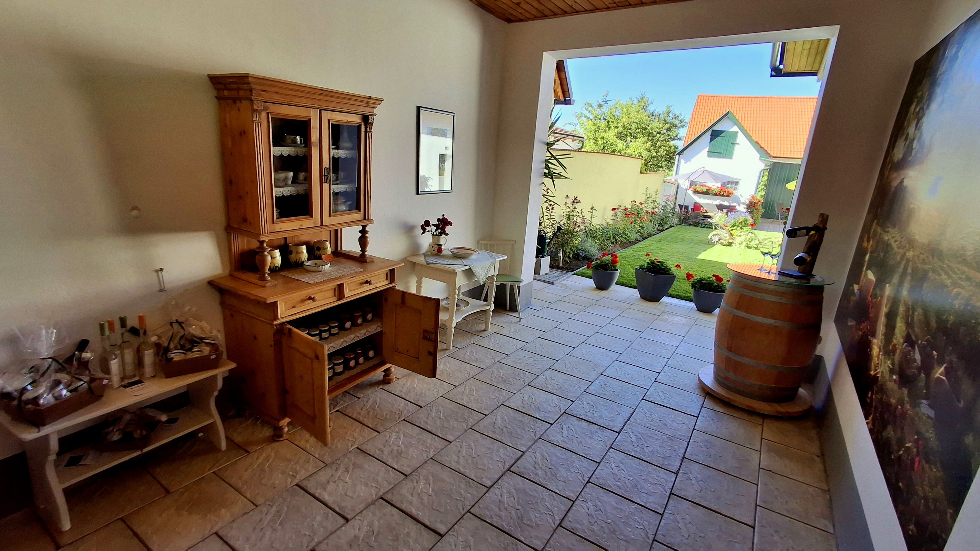 Entrance area with wooden furniture, plants and a view of a garden.