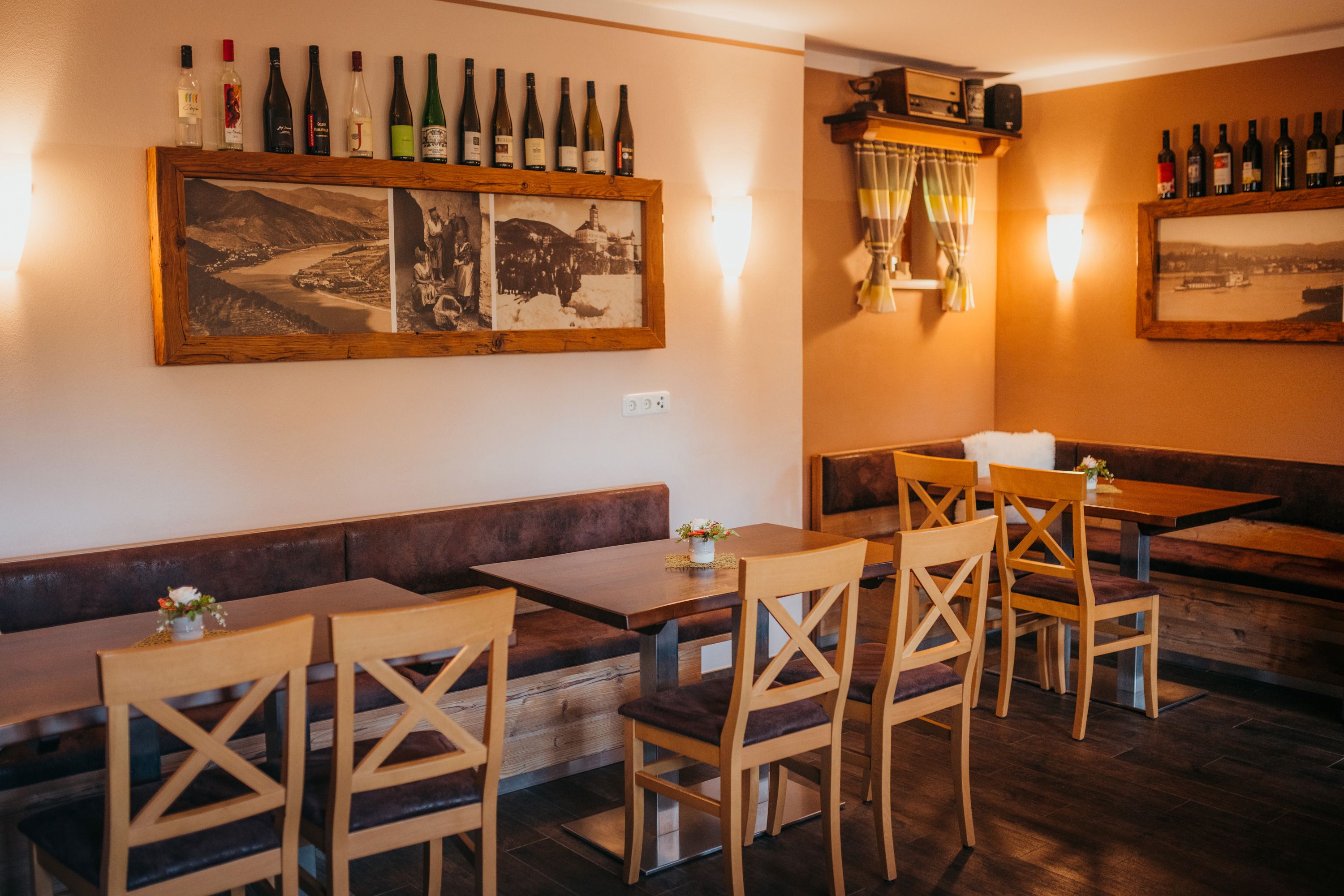 Cozy restaurant with wooden furniture, bottles of wine and historical photos.