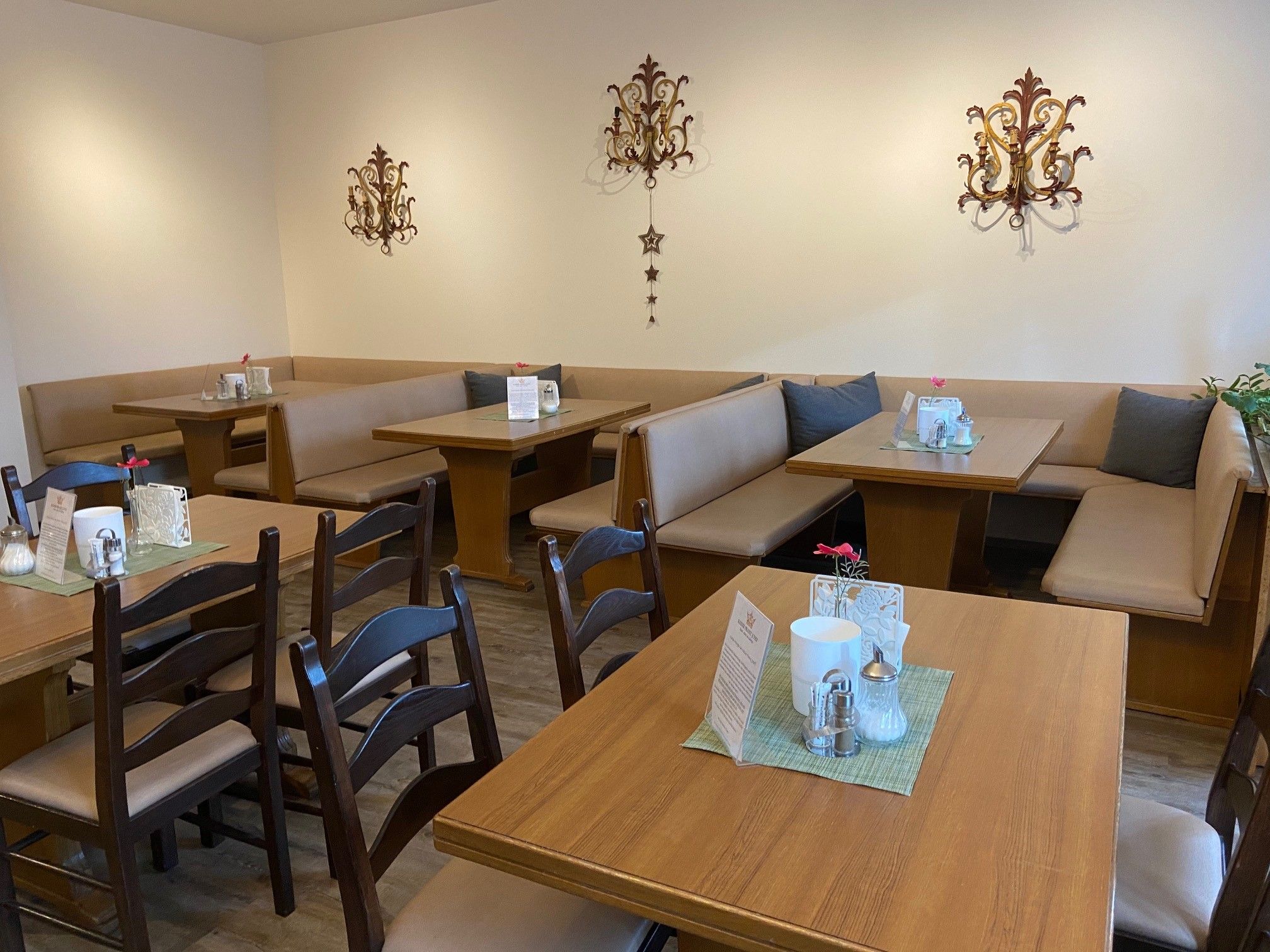 Cozy breakfast area with wooden tables and upholstered benches, decorated with wall ornaments.