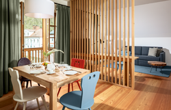 In einem einladenden Raum mit warmen Holztönen und bunten Stühlen entfaltet sich eine gemütliche Atmosphäre, die zum Verweilen einlädt. Der Tisch ist liebevoll gedeckt und verspricht genussvolle Momente in geselliger Runde. Hier wird der Sommer in den Bergen zu einem unvergesslichen Erlebnis.