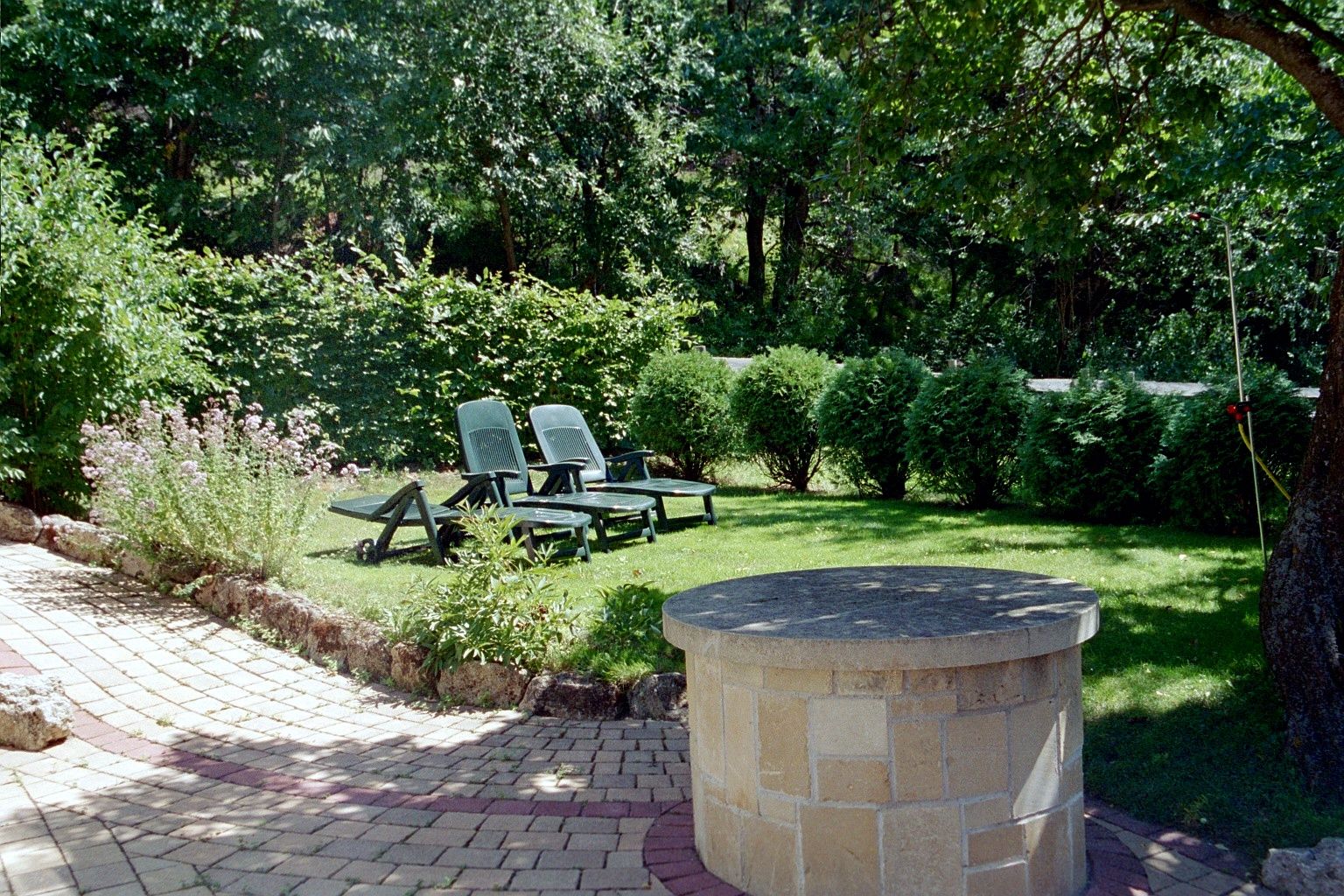 Garden with sun loungers and fountain on a meadow.