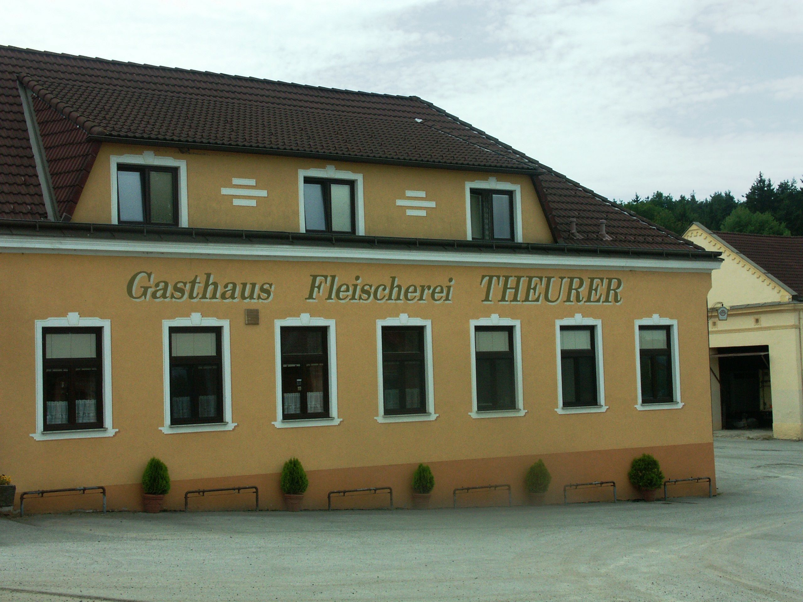 Exterior view of the Theurer inn and butcher's shop with yellow façade and brown roof.
