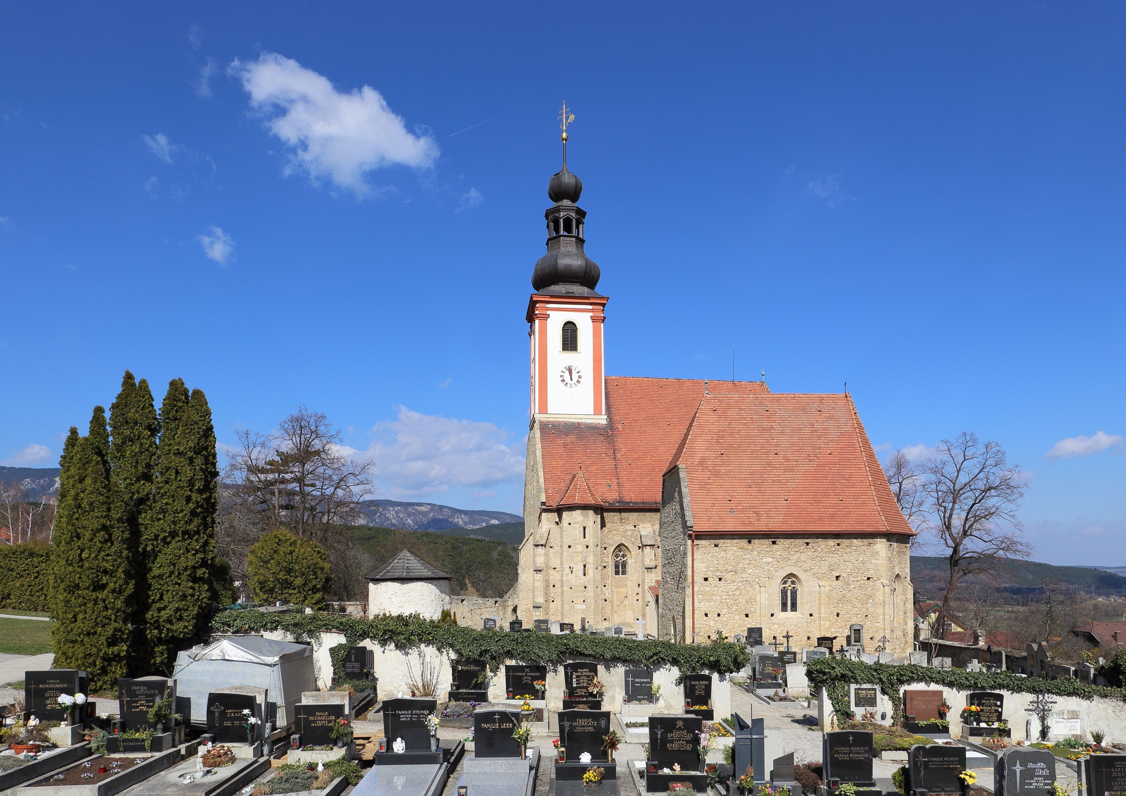 Church with cemetery in the foreground and blue sky.