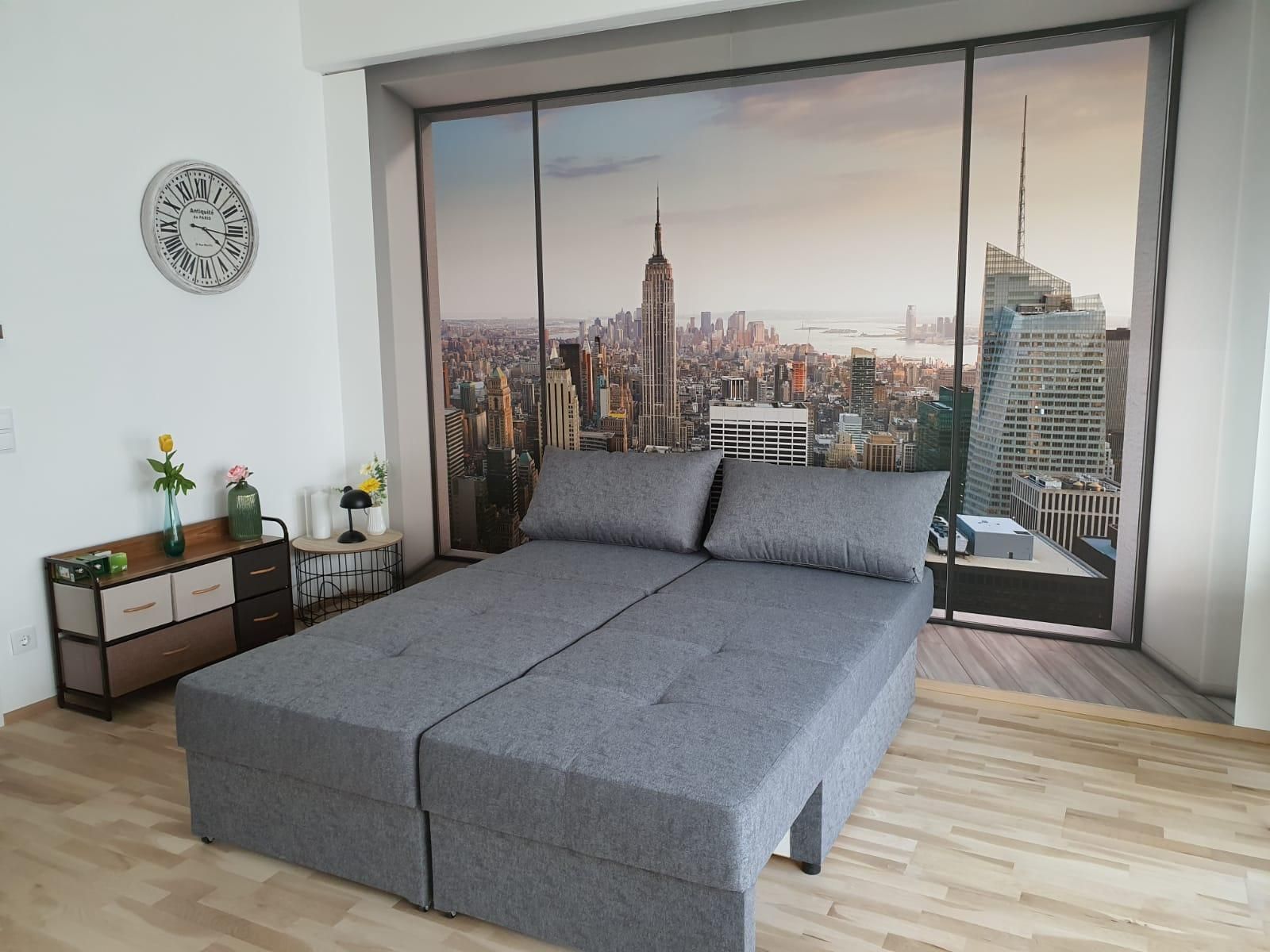 Room with gray sofa and photo wallpaper of New York skyline.