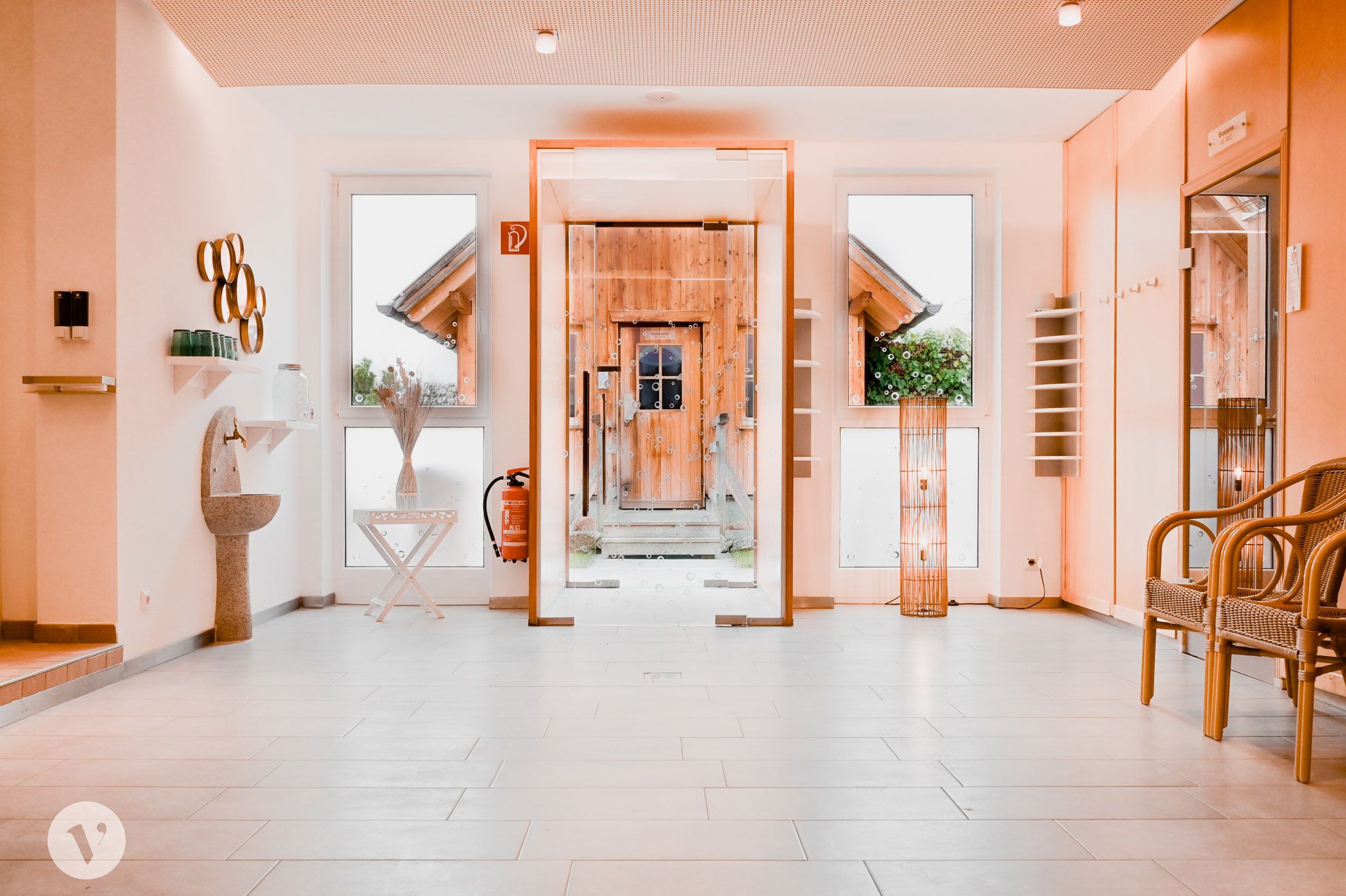 Modern lounge area with glass wall, wooden door, decorations and seating.
