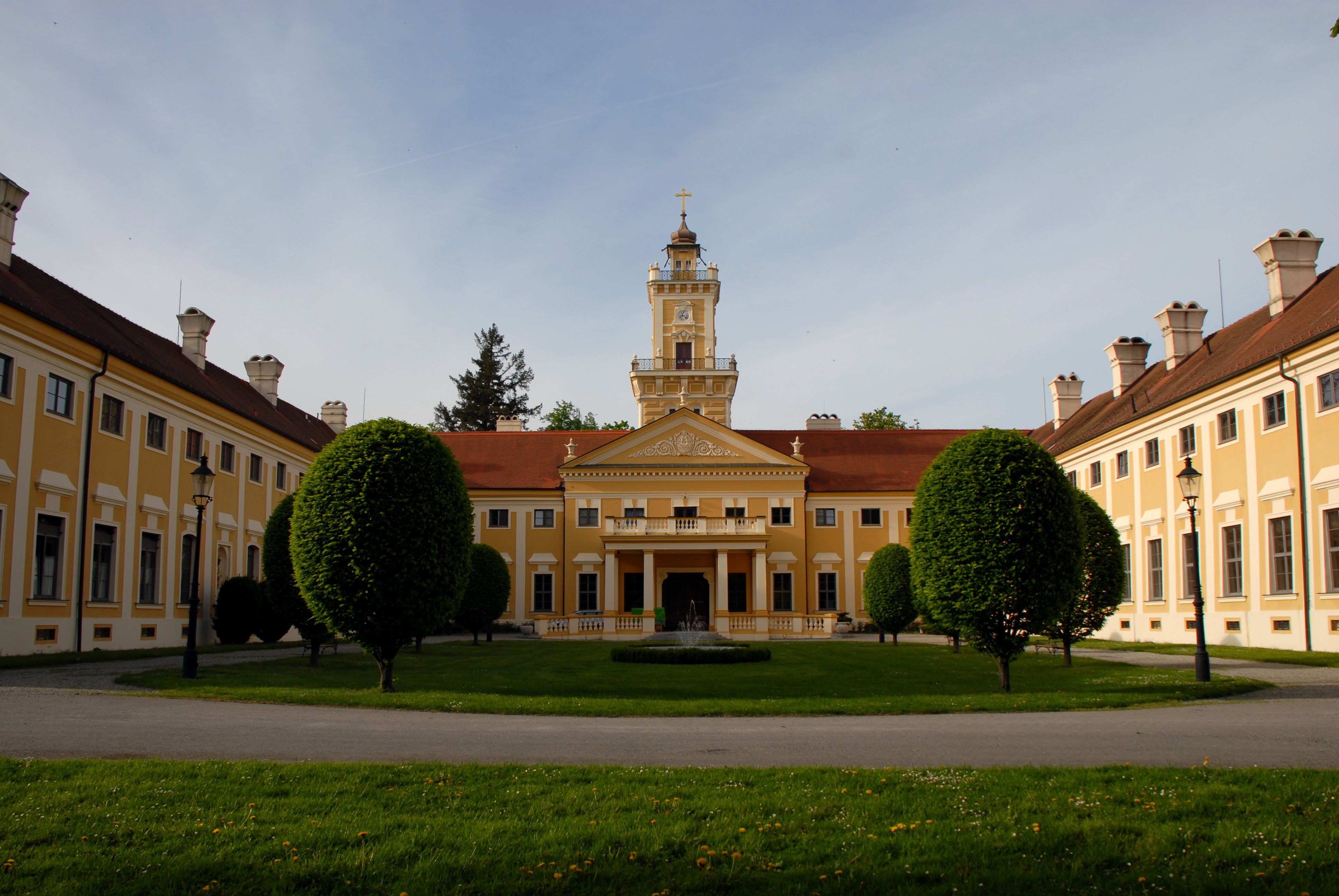 Jaidhof Castle with yellow façade and tower, surrounded by a well-tended garden.