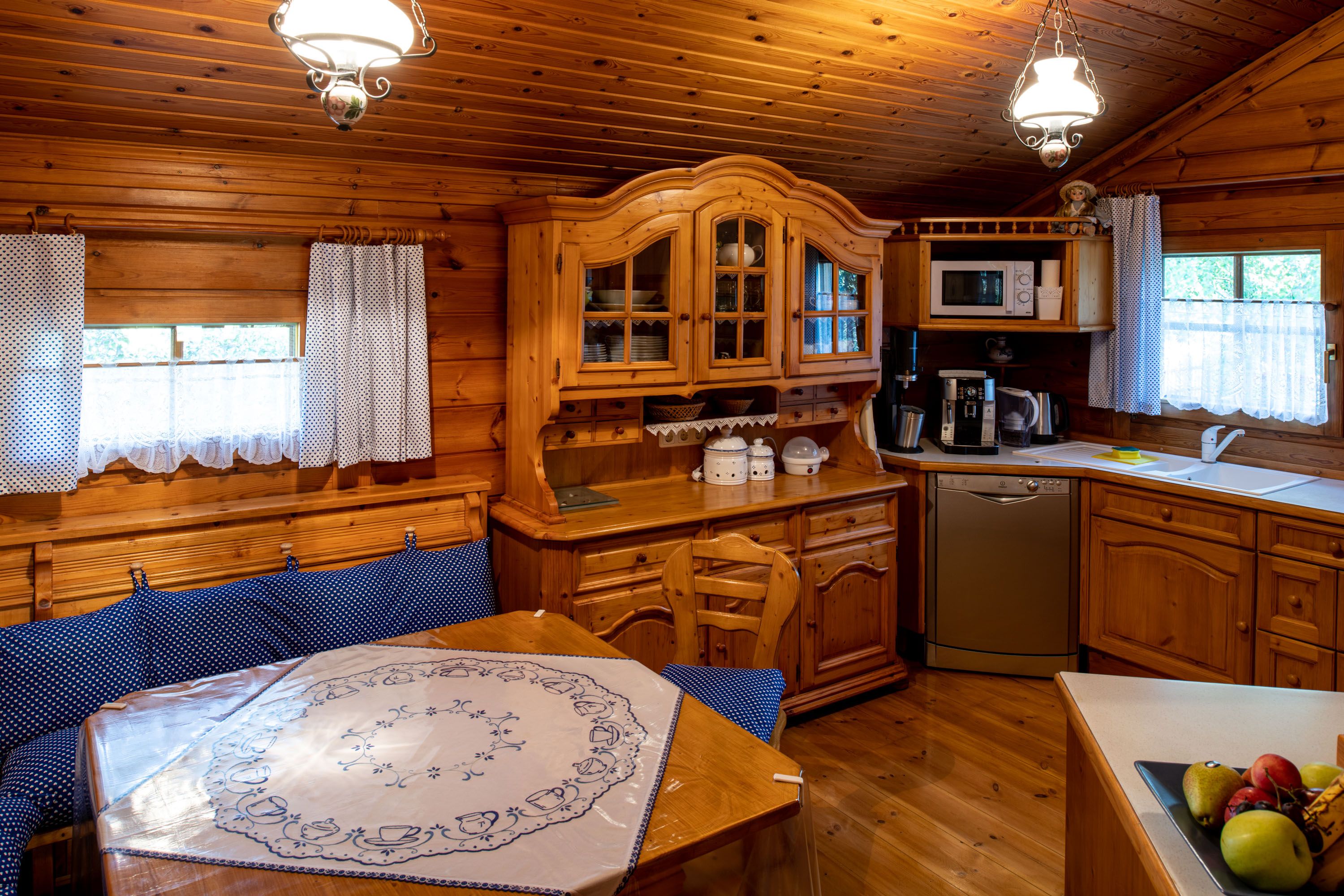 Cozy wooden kitchen with dining area, blue upholstery and tablecloth. Rustic furniture, dishwasher, microwave and coffee machine available.
