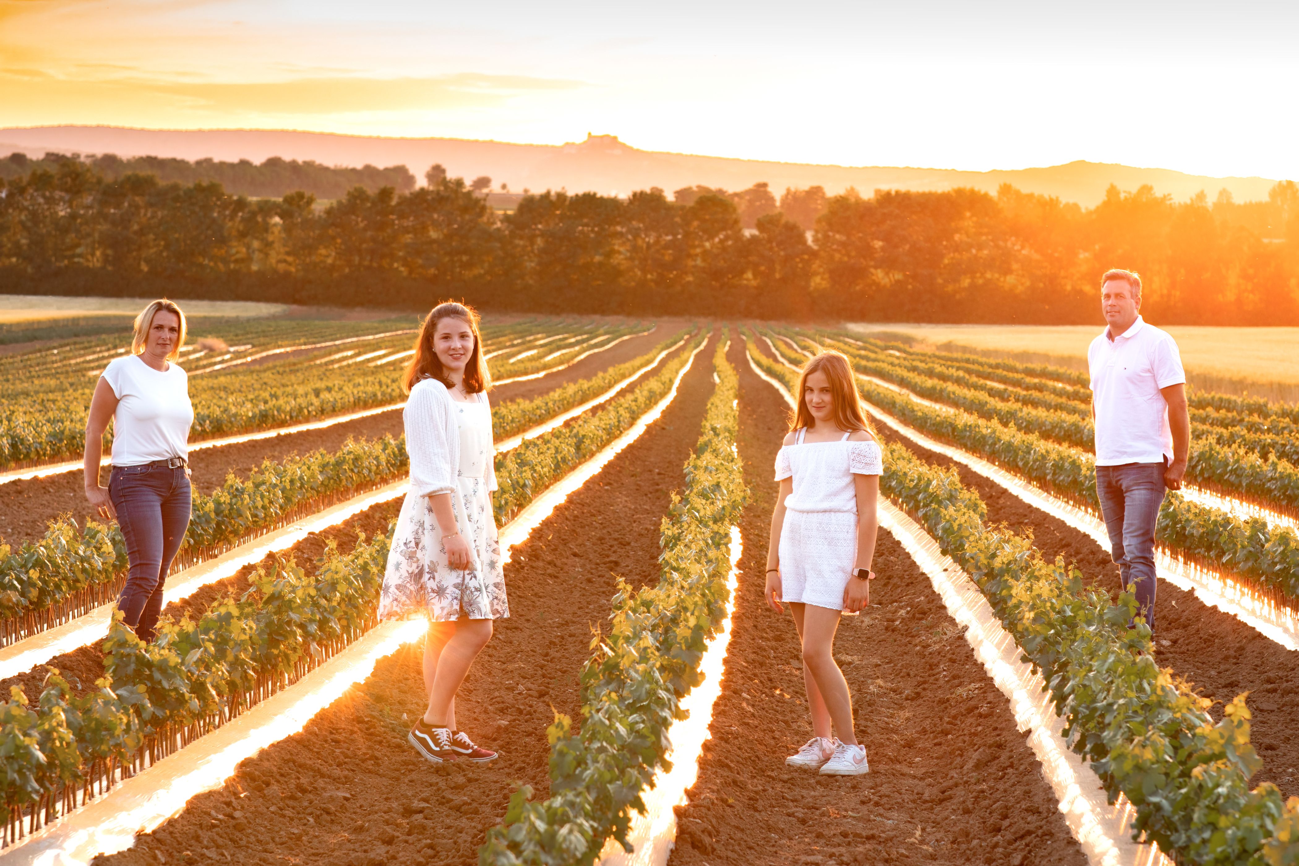 A family stands in a field at sunset.