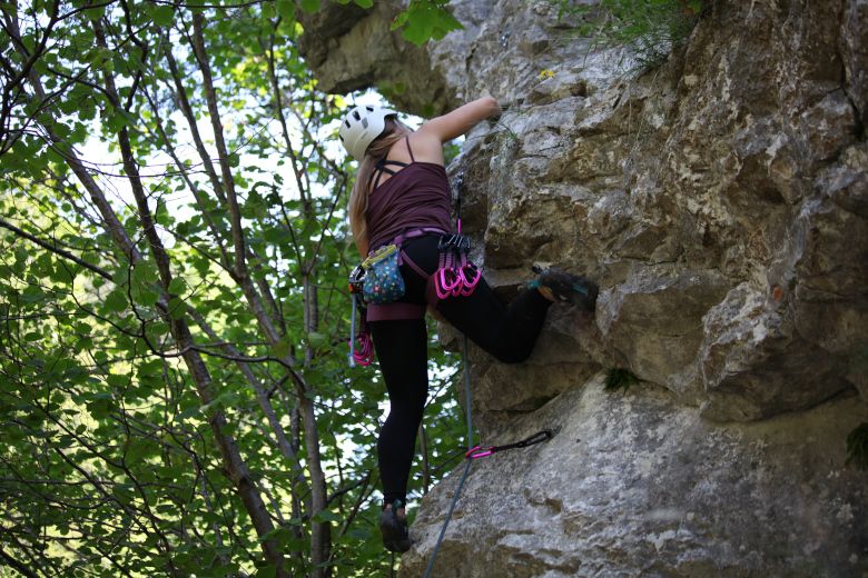Person climbing on a rock face in the forest.