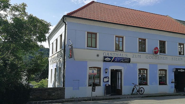 A two-storey building with the inscription 'Gasthaus zum Goldenen Stern' and a bicycle in front of it.