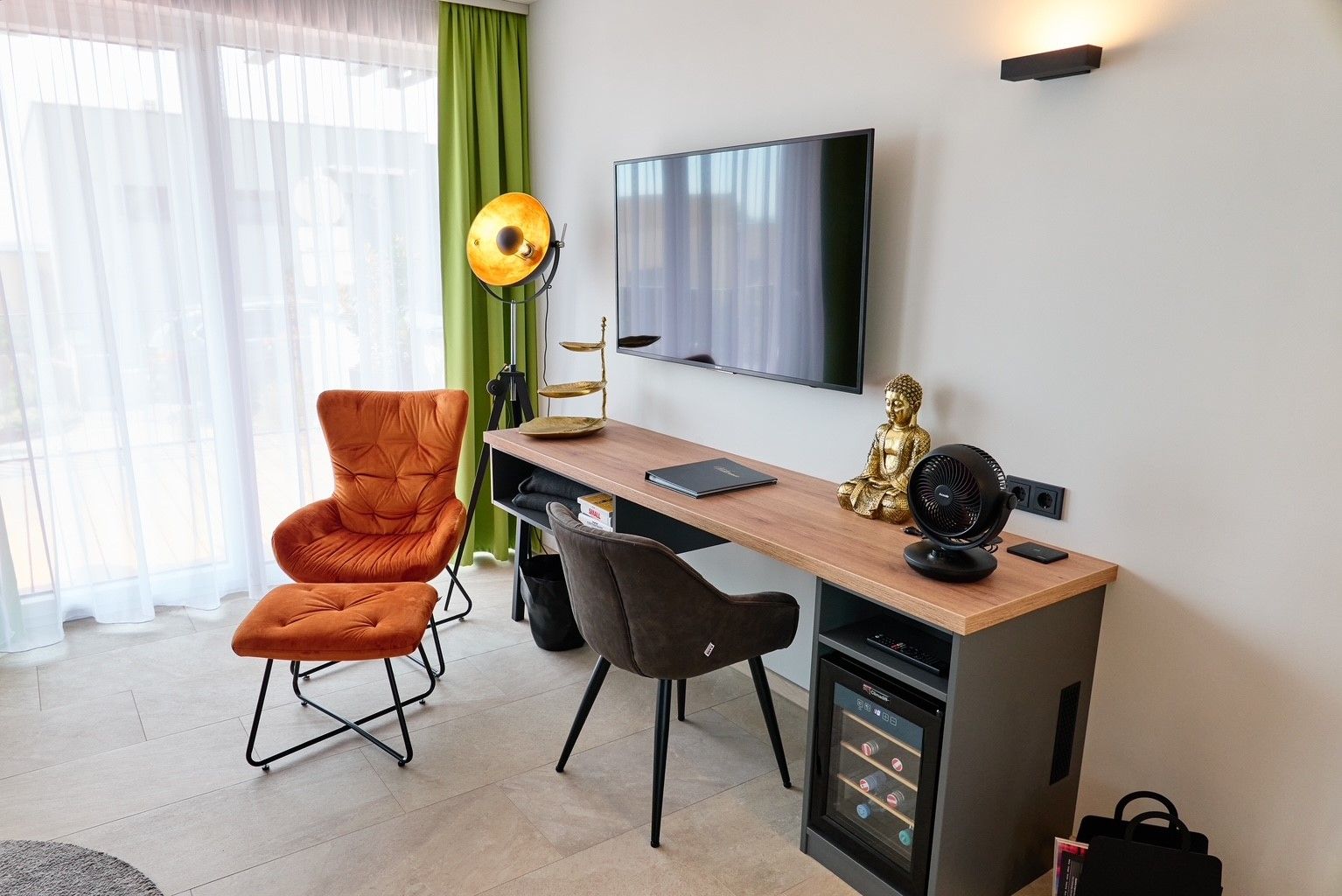 Living room with armchair, desk, Buddha statue and TV.