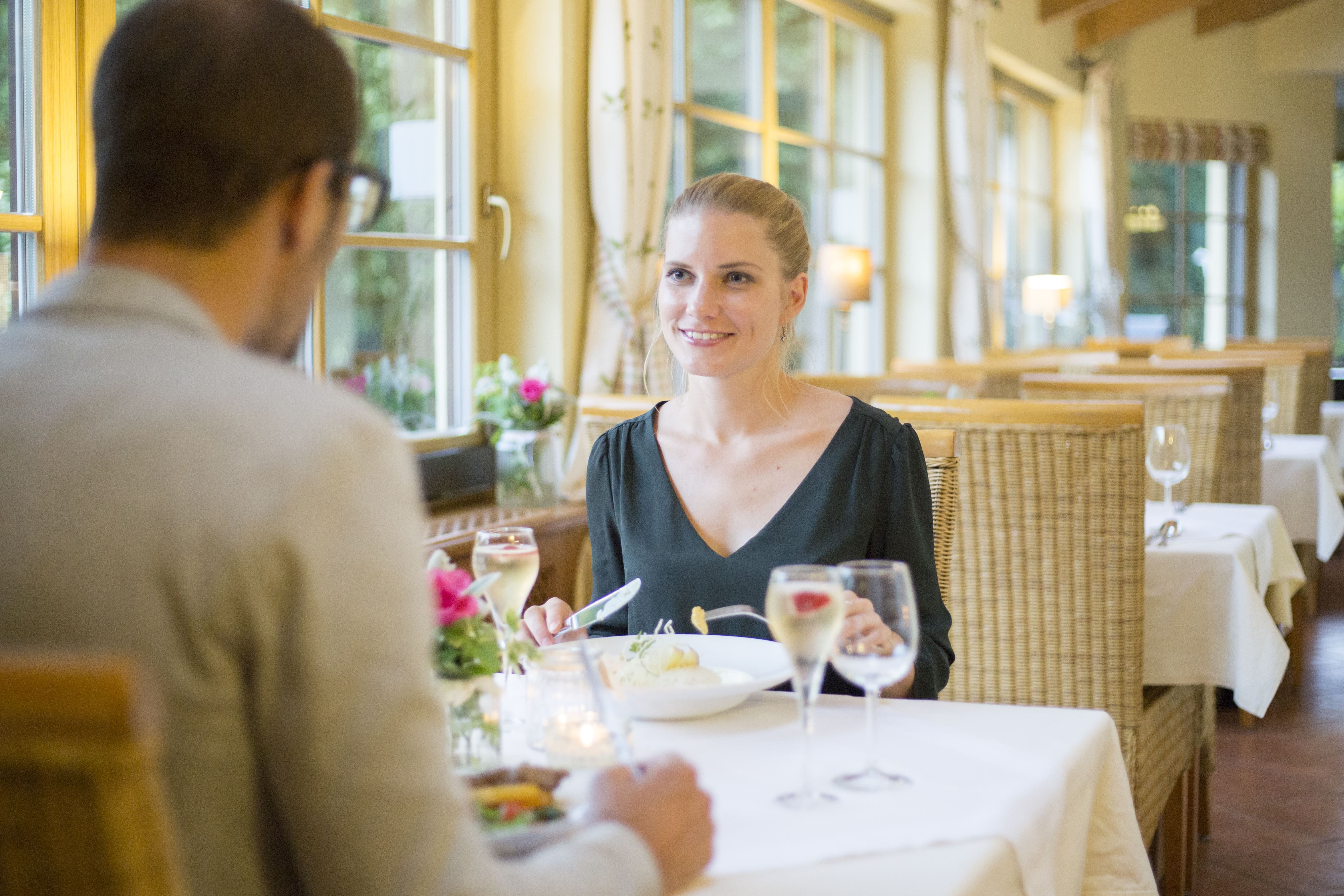 A couple having dinner in a cozy restaurant with large windows and candlelight.