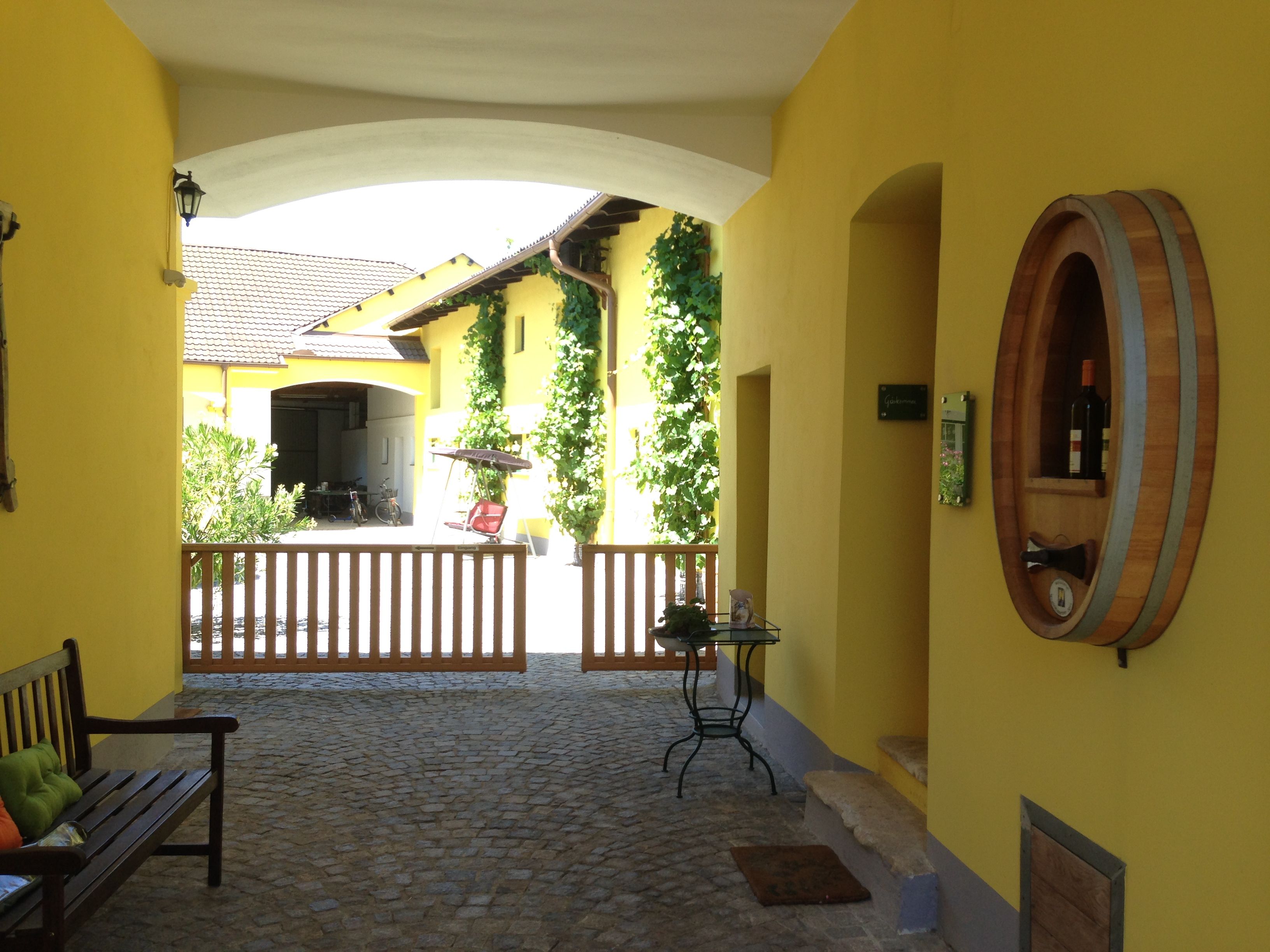 Inner courtyard of a yellow building with wine barrel decoration and wooden gate.