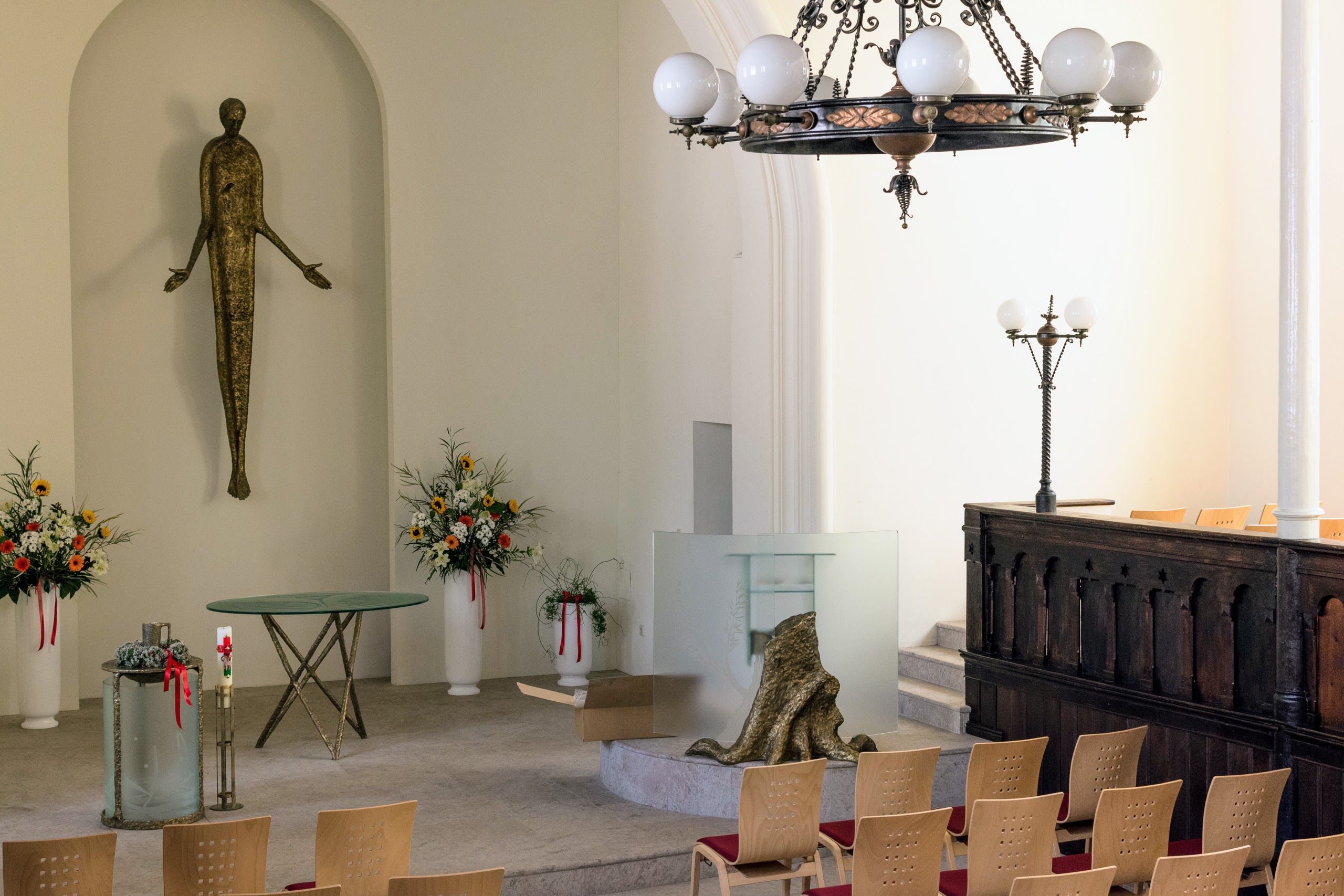 Interior of a church with modern decoration, flower arrangements and a statue.