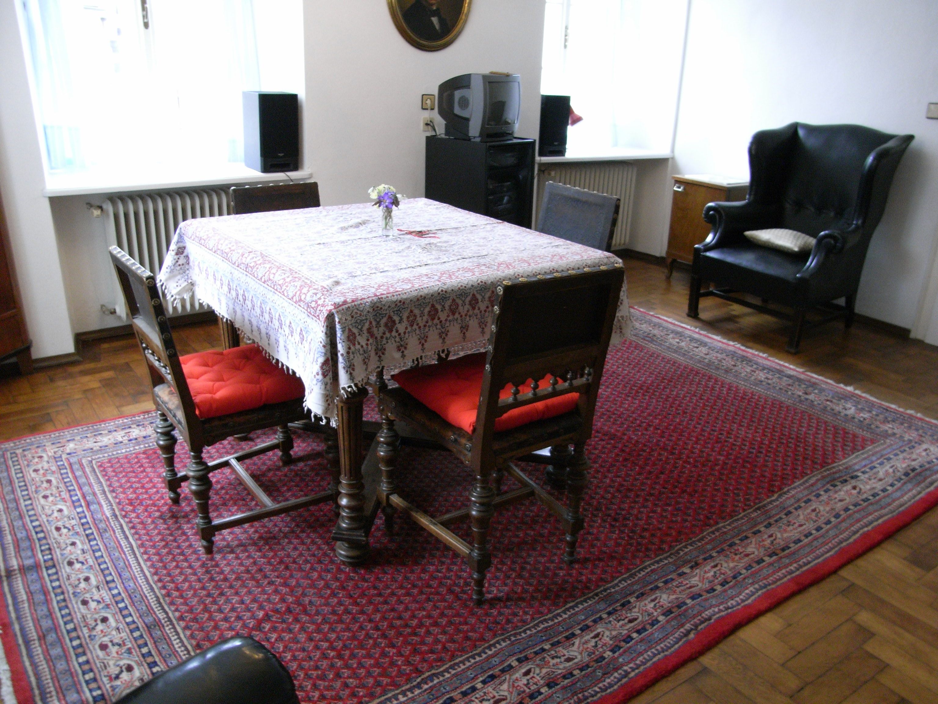 Living room with table, chairs and carpet.