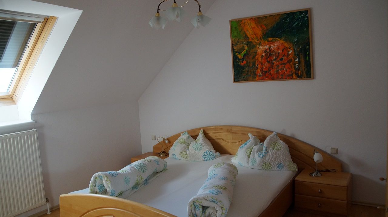 Bedroom with double bed, skylight and abstract painting on the wall.