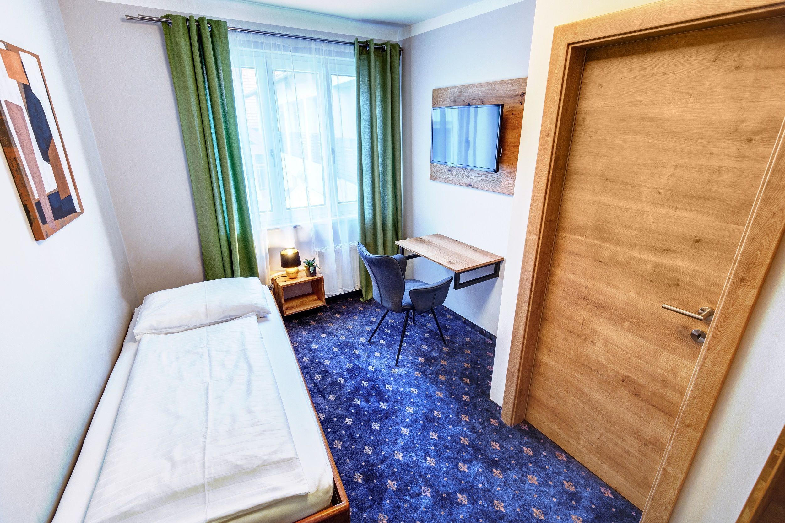 Single room with desk and window, blue carpet 