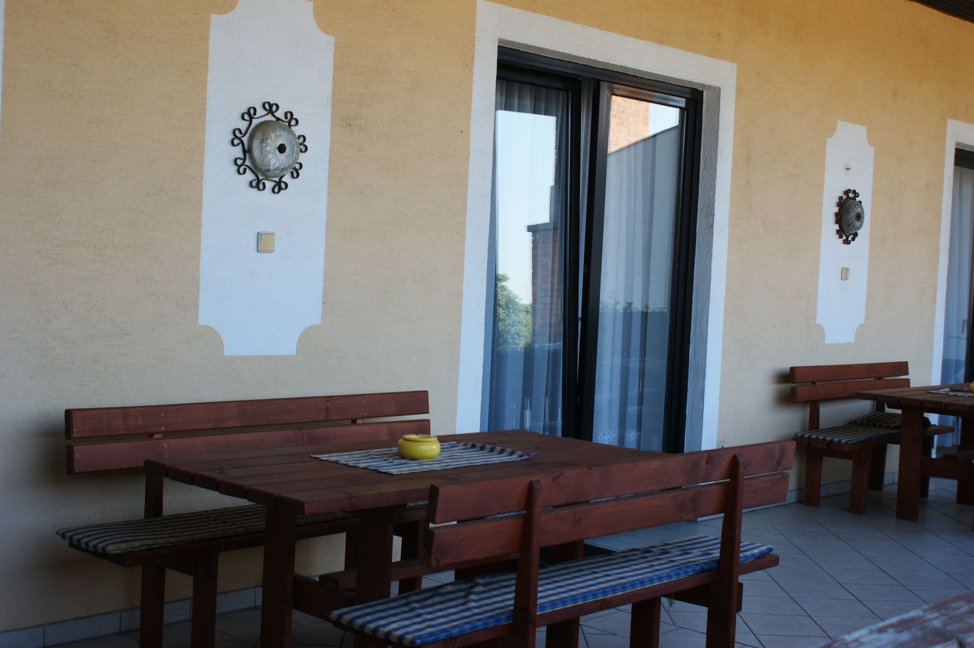 Terrace with wooden tables and benches, decorated with wall ornaments.