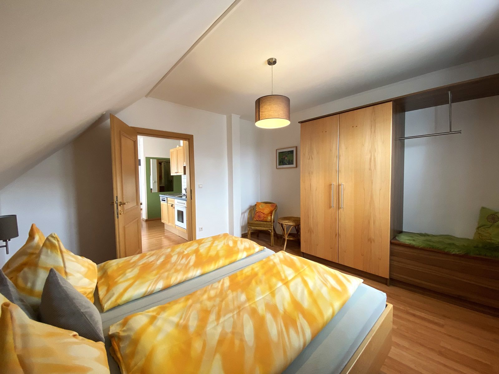 Bedroom with double bed, closet and view into the kitchen.