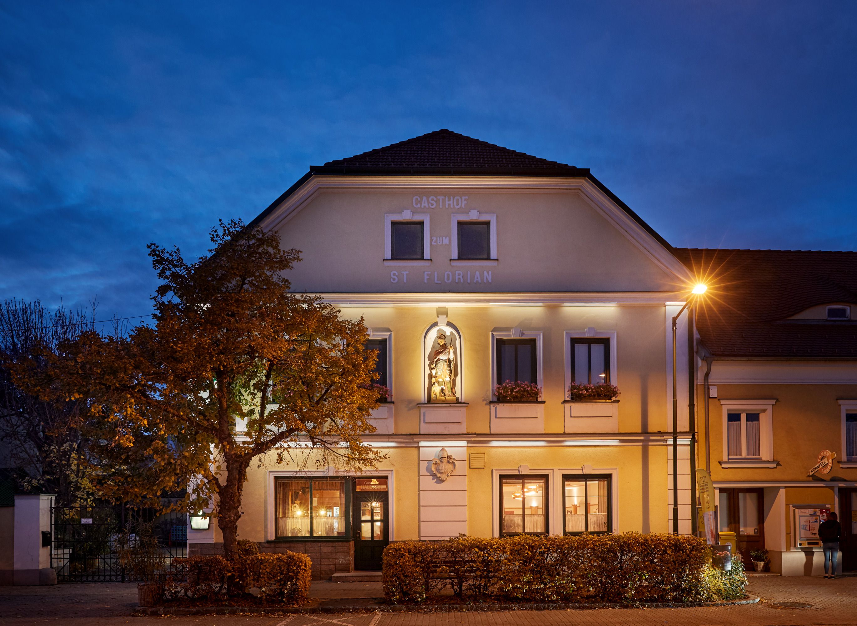 St. Florian Inn at dusk with illuminated façade and statue.