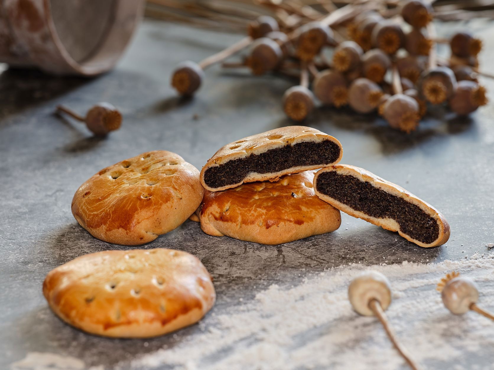 Poppy seed cookies on a table with poppy seed capsules in the background.
