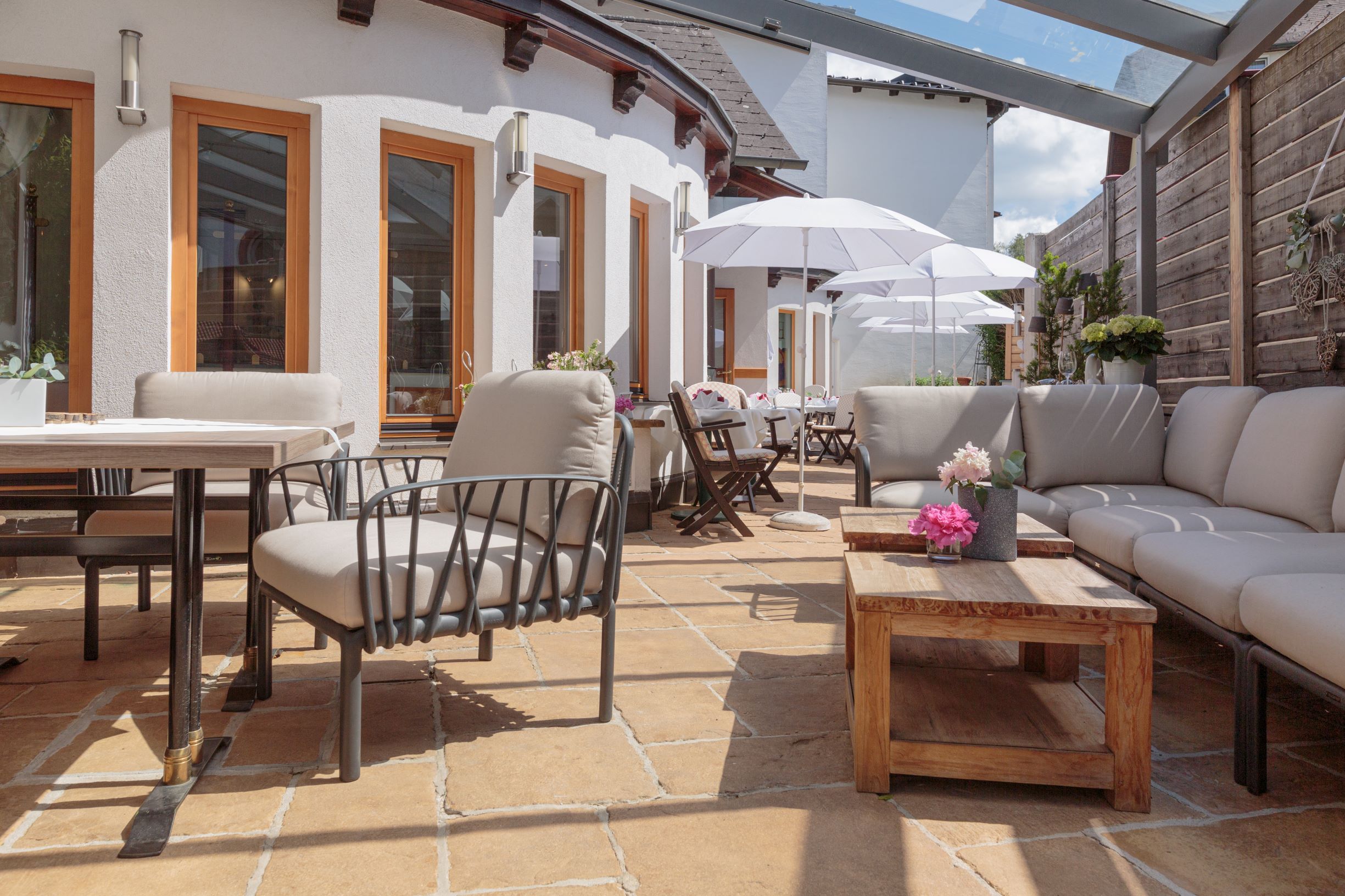 Modern terrace with comfortable seating, wooden tables and parasols.
