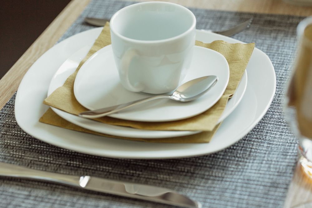 Table set with white crockery, cup and cutlery.