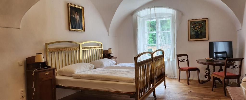 A cozy guest room with a double bed, wooden furniture and a large window with curtains.