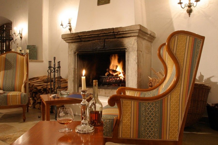 Cozy fireplace lounge with a burning fireplace, armchairs and table with drinks.