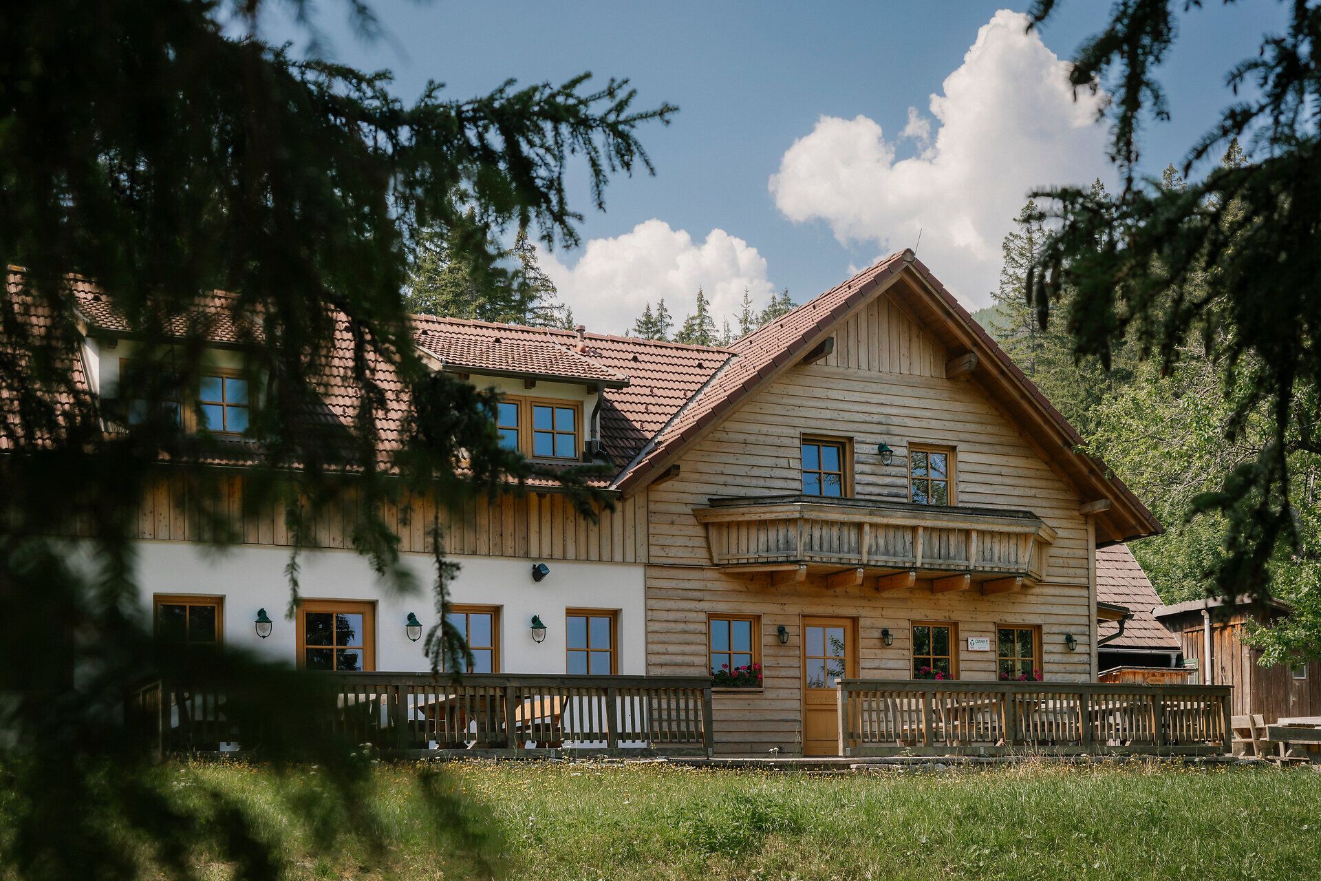 Exterior view of the Hengsthütte on the Schneeberg, featuring a wooden balcony and terrace