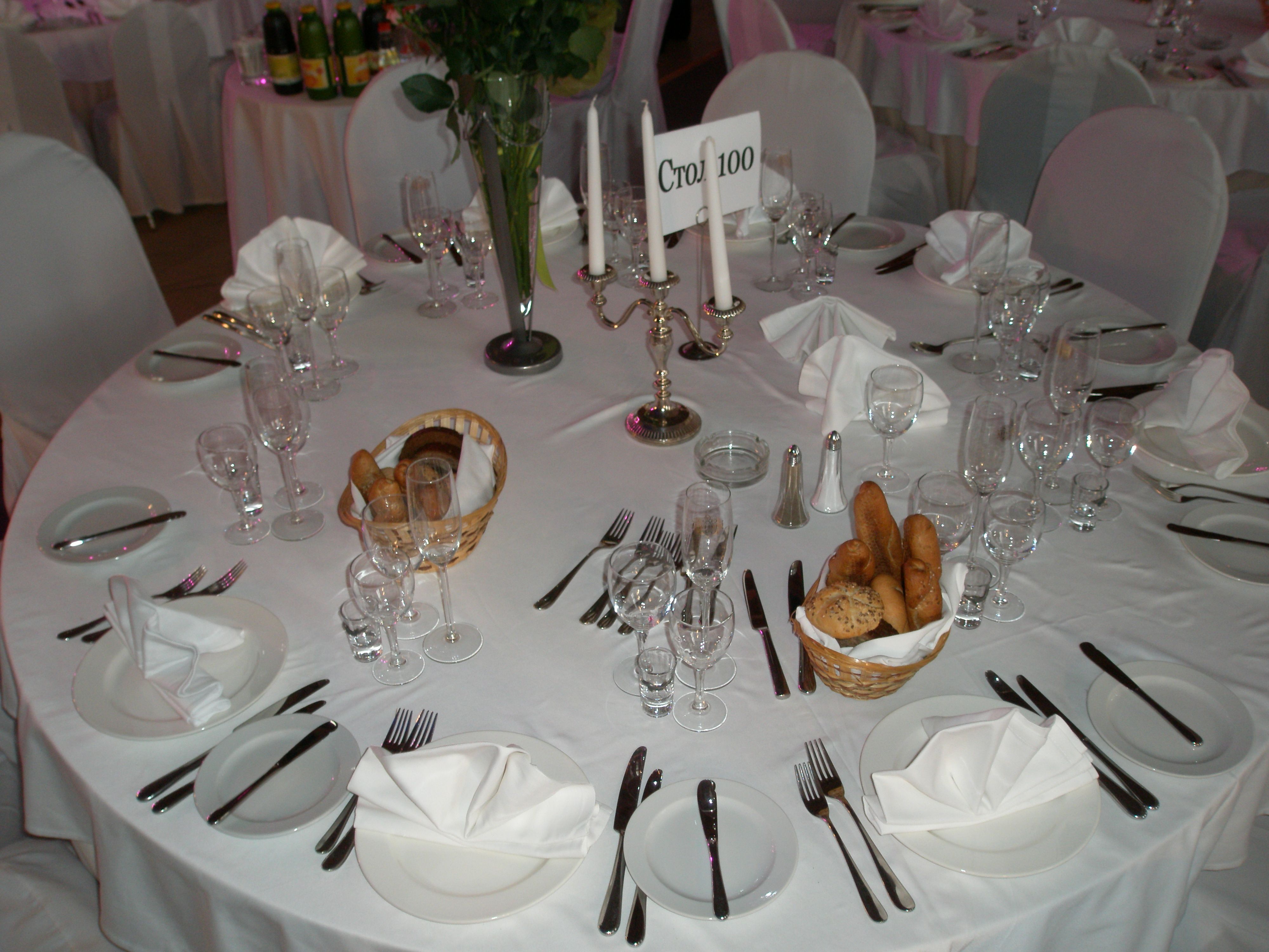 Elegant table setting with white tablecloths, candlesticks and bread baskets.