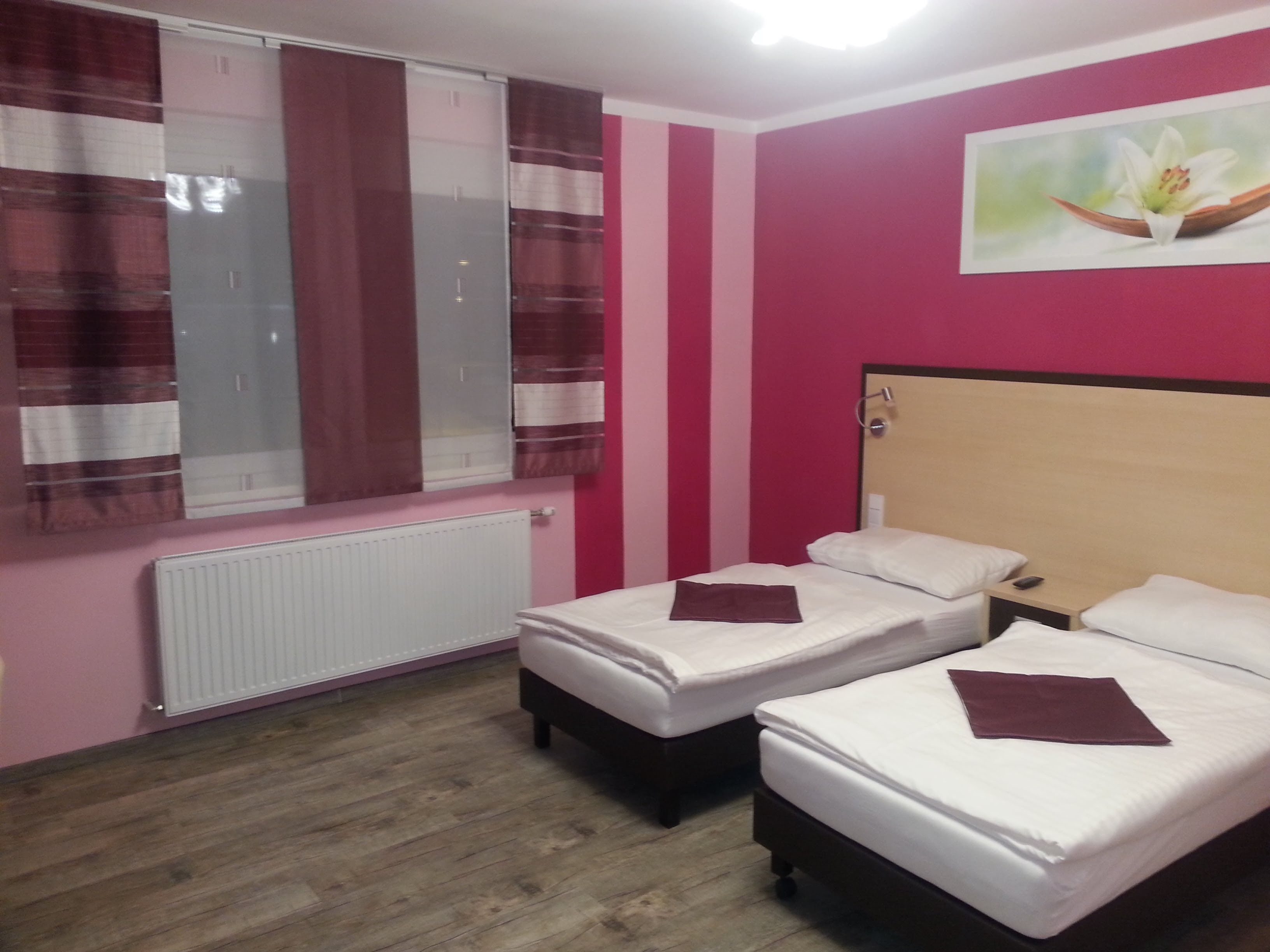 Twin room with two single beds, pink walls and a picture of a flower on the wall.