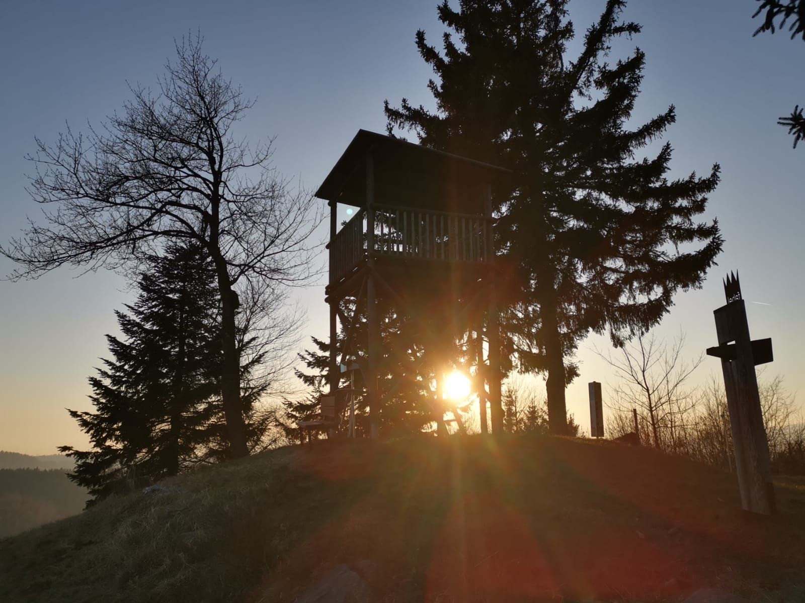 Sunset behind a lookout tower and trees.