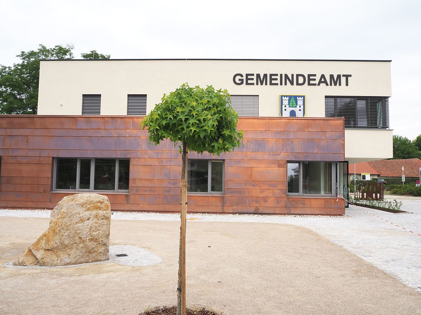 Modern building of the Sieghartskirchen municipal office with tree and stone in the foreground.
