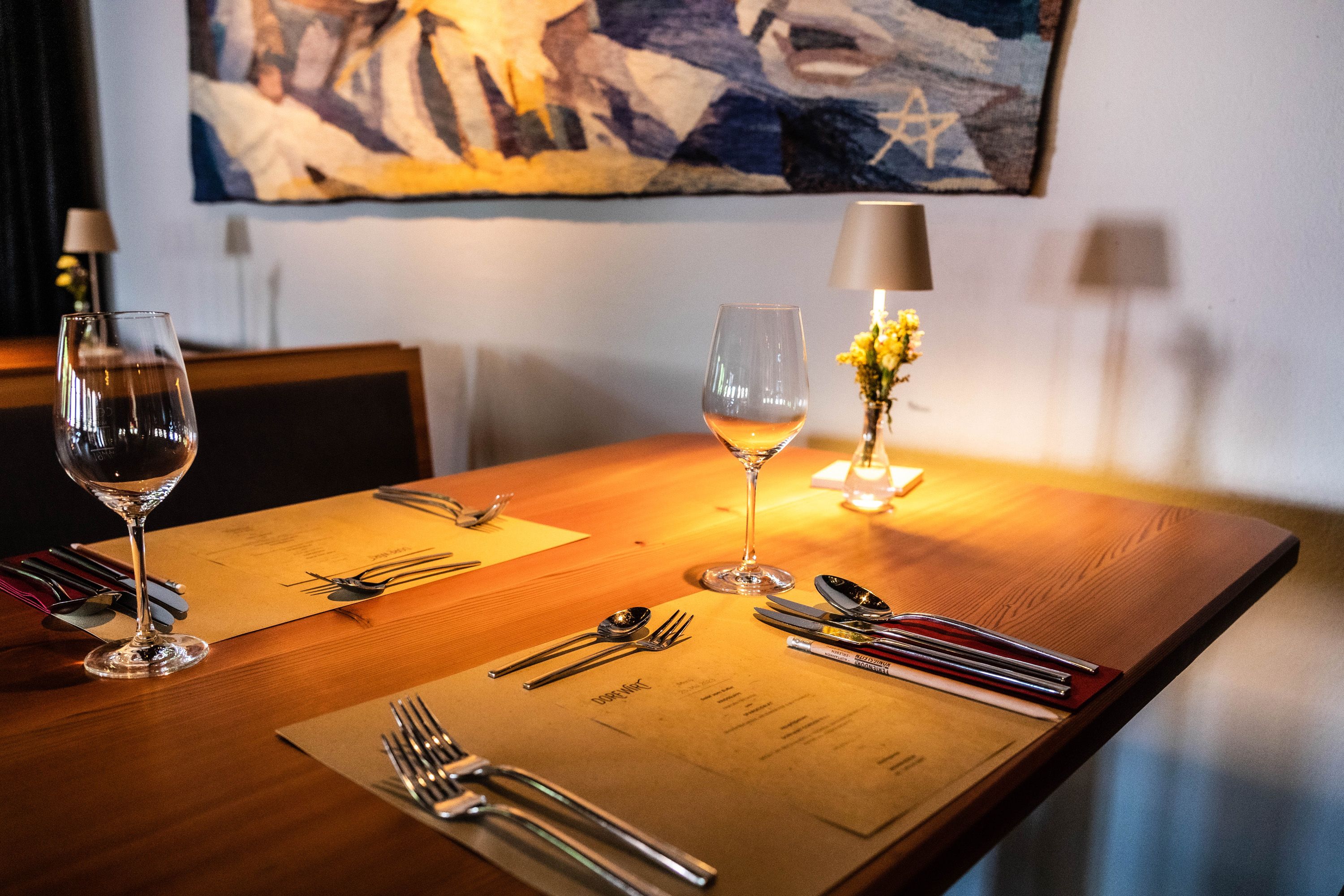Elegant table in a restaurant with wine glasses, cutlery and flowers.
