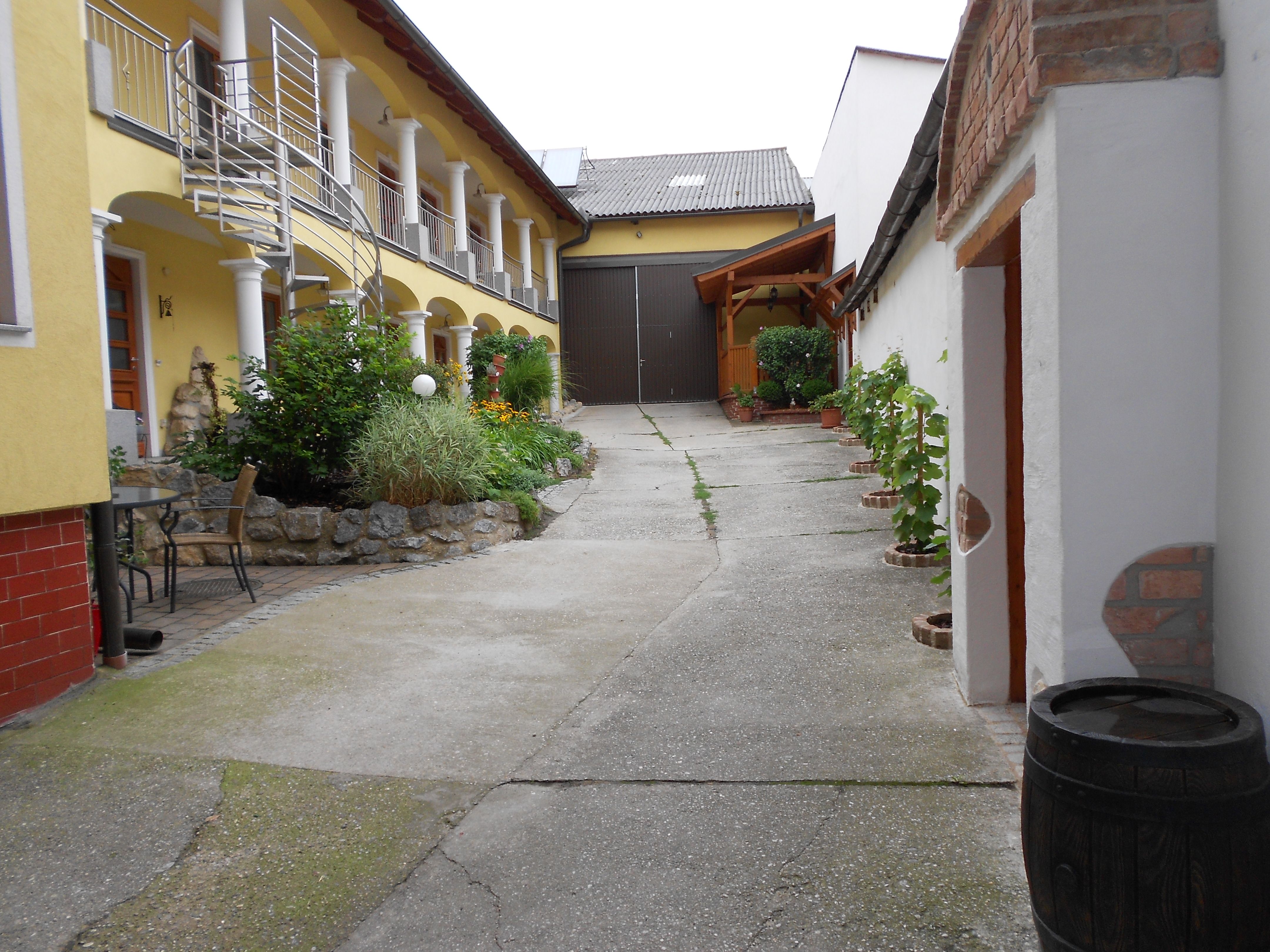 An inner courtyard with a yellow building, plants and a metal staircase.