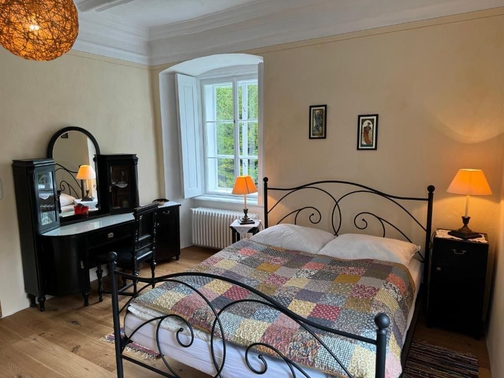 Cozy guest room with double bed, antique dressing table and warm light.